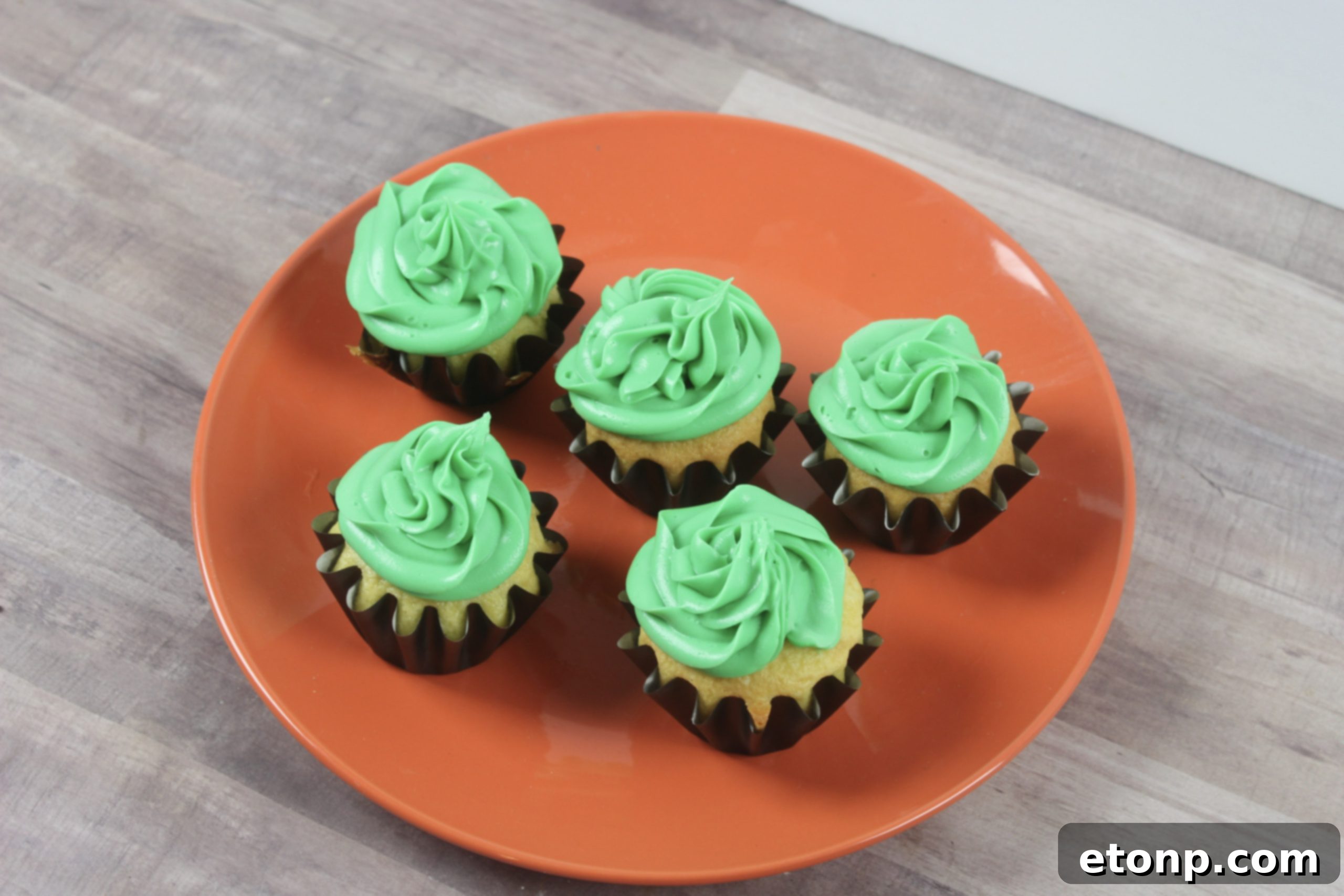 Mixing green food dye into white frosting to achieve a vibrant witchy color