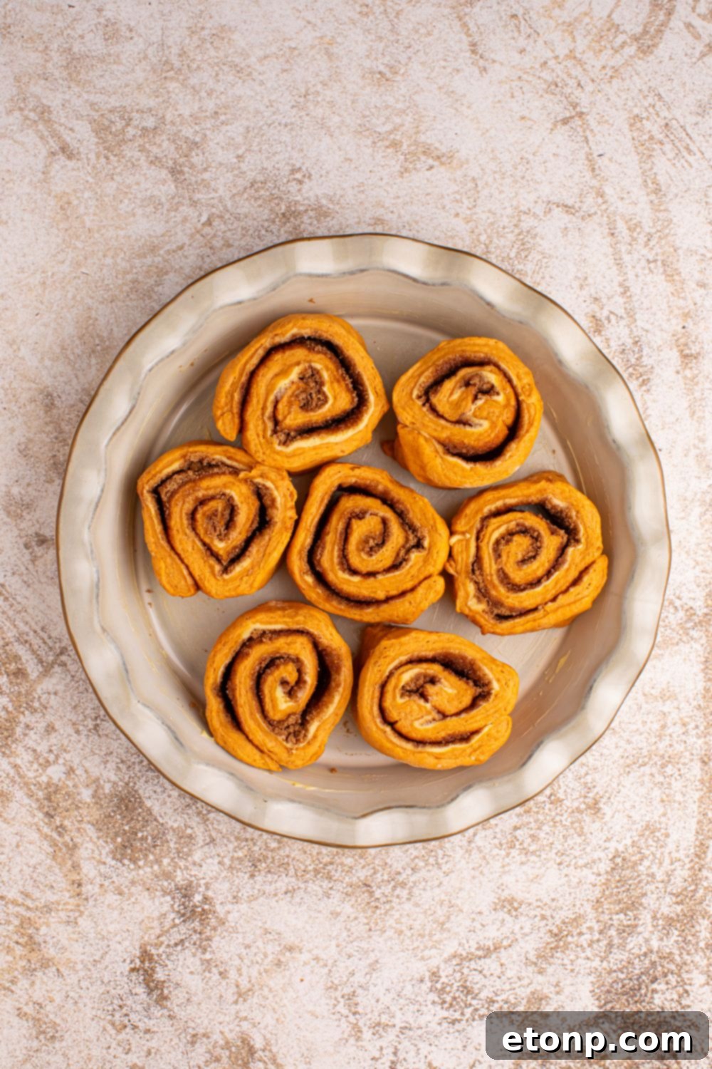 Effortless 2-Ingredient Pumpkin Cinnamon Rolls No Yeast 12 raw Pumpkin Cinnamon Rolls in a pie plate on counter