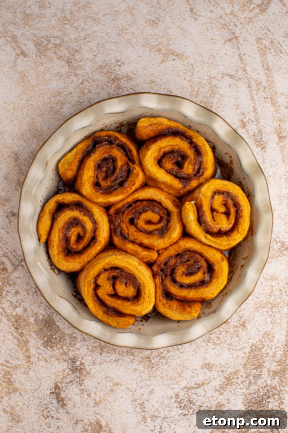 Effortless 2-Ingredient Pumpkin Cinnamon Rolls No Yeast 13 baked Pumpkin Cinnamon Rolls in a pie plate sitting on counter