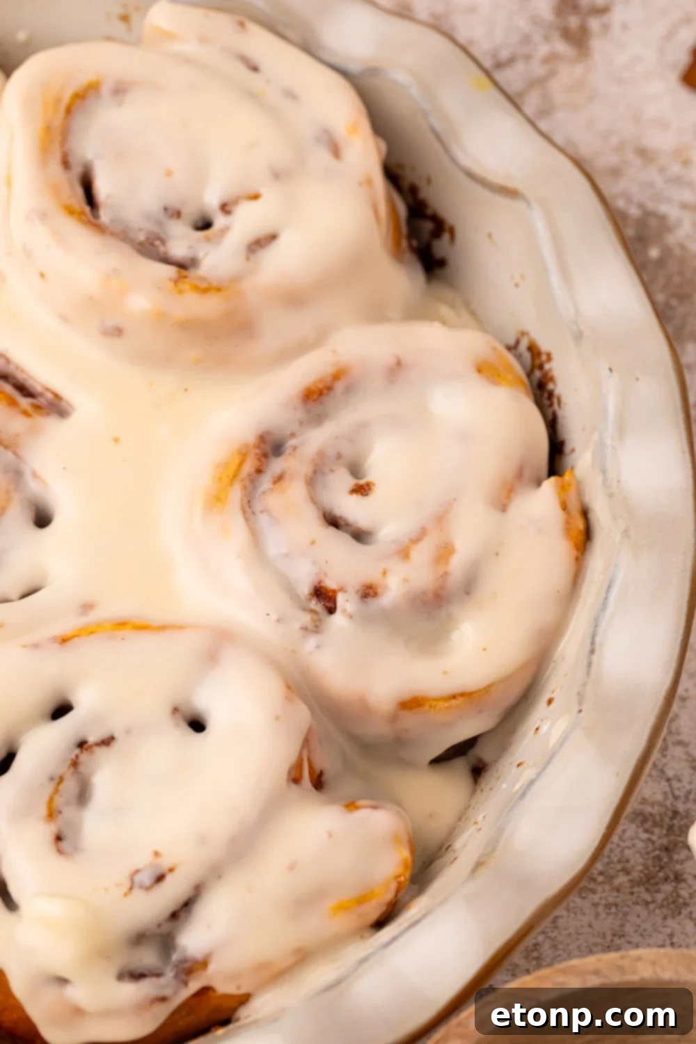 Effortless 2-Ingredient Pumpkin Cinnamon Rolls No Yeast 15 Pumpkin Cinnamon Rolls in a pie plate dish on table with a glaze drizzled over the top of the rolls