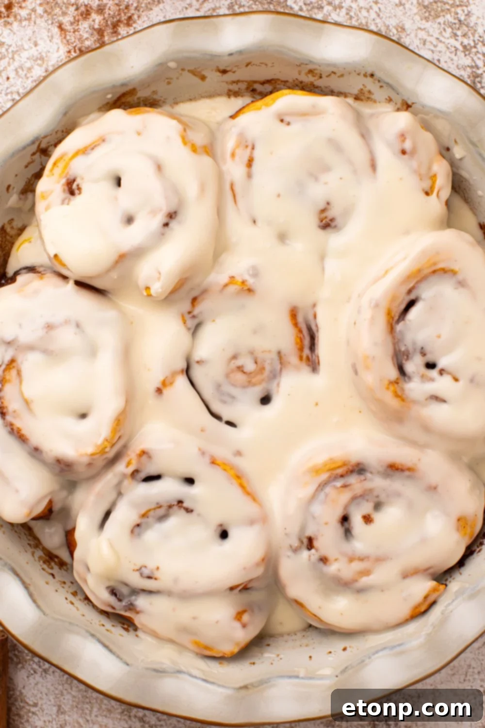 Effortless 2-Ingredient Pumpkin Cinnamon Rolls No Yeast 16 looking down at table to a round pie plate full of baked and glazed Pumpkin Cinnamon Rolls on the table