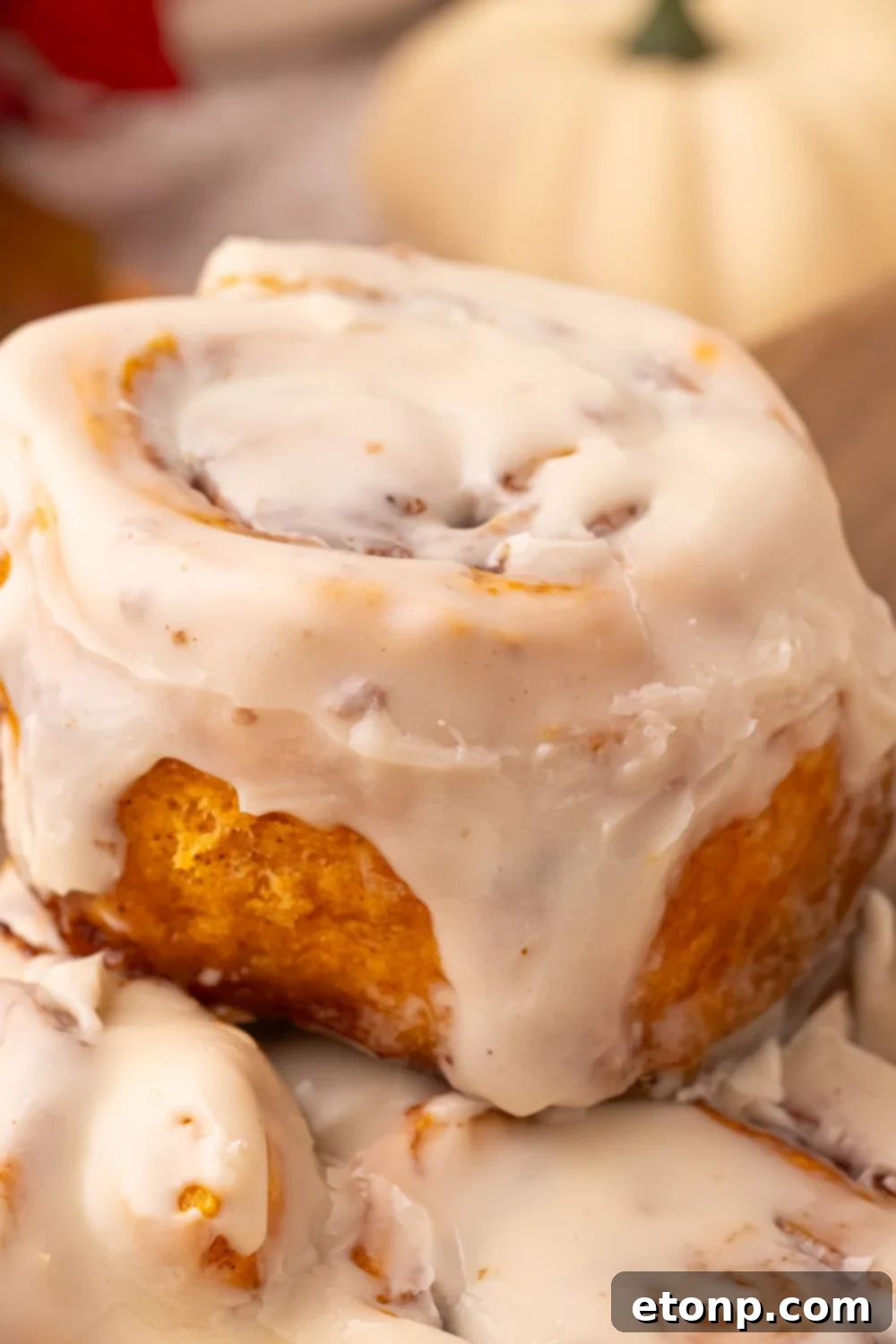 Effortless 2-Ingredient Pumpkin Cinnamon Rolls No Yeast 18 close up of Pumpkin Cinnamon Roll being lifted out of pan with glaze drizzling down the side of roll