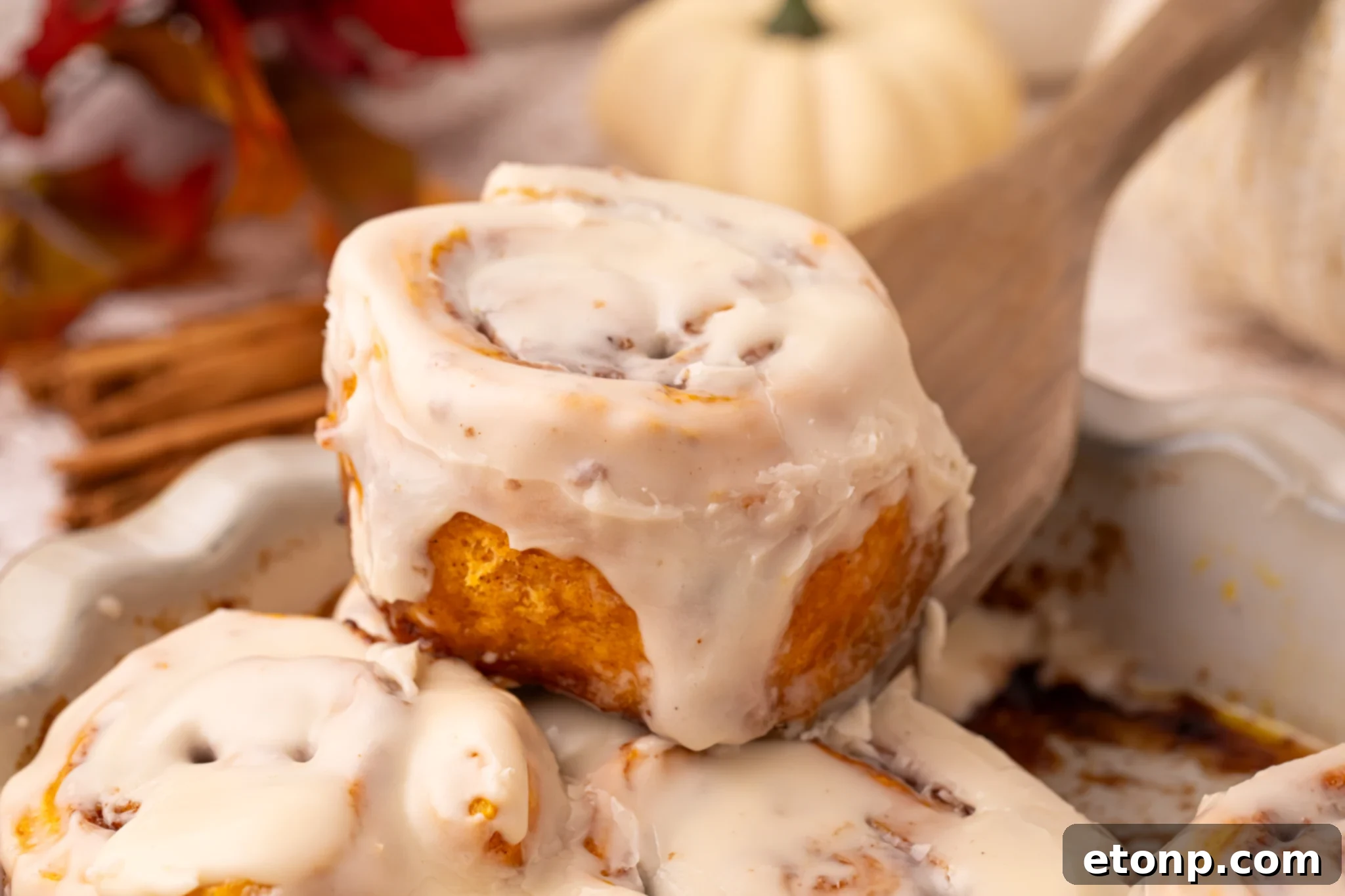 Effortless 2-Ingredient Pumpkin Cinnamon Rolls No Yeast 23 Easy 2 Ingredient Pumpkin Cinnamon Rolls in a baking dish smothered in icing with one being lifted up
