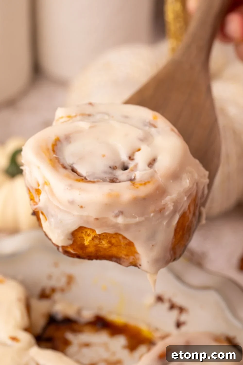 Effortless 2-Ingredient Pumpkin Cinnamon Rolls No Yeast 26 Pumpkin Cinnamon Rolls in a pie plate on table with a cinnamon roll scooping up out of pan, with a fall themed look on table