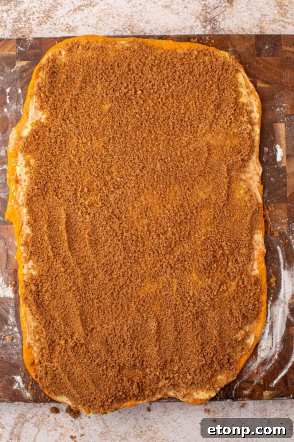 Effortless 2-Ingredient Pumpkin Cinnamon Rolls No Yeast 10 rolled out pumpkin cinnamon roll dough with cinnamon and sugar mixture spread over the top of it