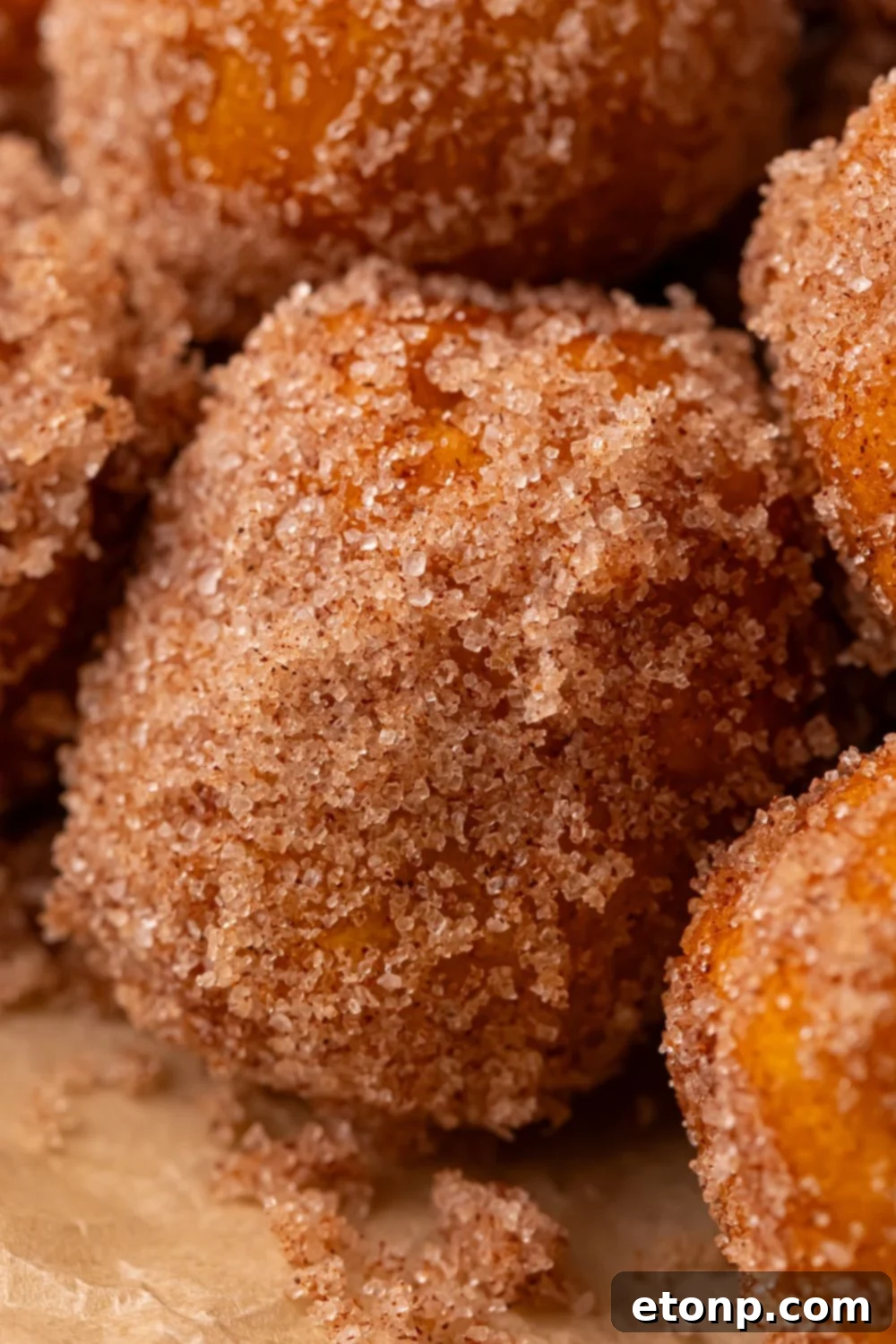 Effortless Two-Ingredient Pumpkin Pie Bites 11 close up of a cinnamon sugar coated Pumpkin Pie Donut Holes stacked on top of one another