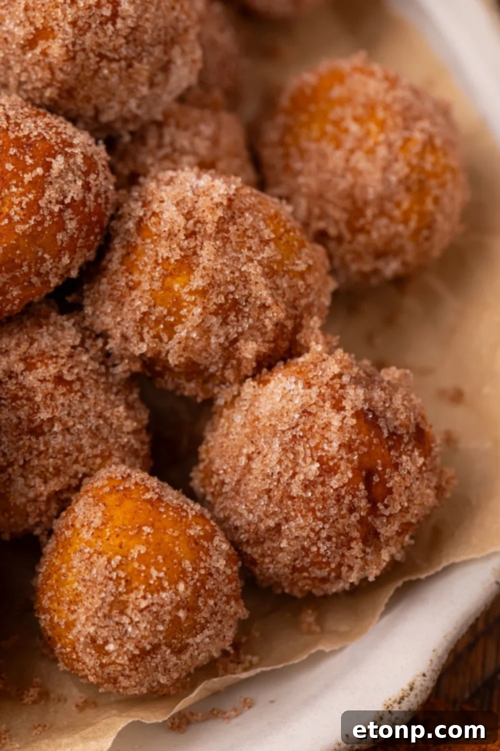 Effortless Two-Ingredient Pumpkin Pie Bites 15 close up of a white plate full of a stack of Pumpkin Pie Donut Holes. You get a close up look of the cinnamon and sugar coating