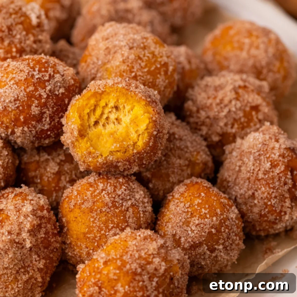 Effortless Two-Ingredient Pumpkin Pie Bites 3 2 Ingredient Pumpkin Pie Donut Holes on table with a bite taken out of one of the rolls