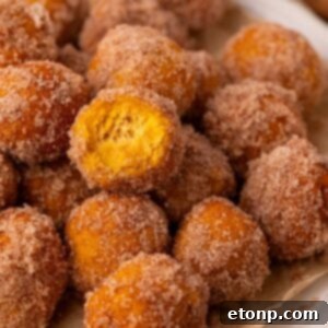 2 Ingredient Pumpkin Pie Donut Holes on table with a bite taken out of one of the donuts