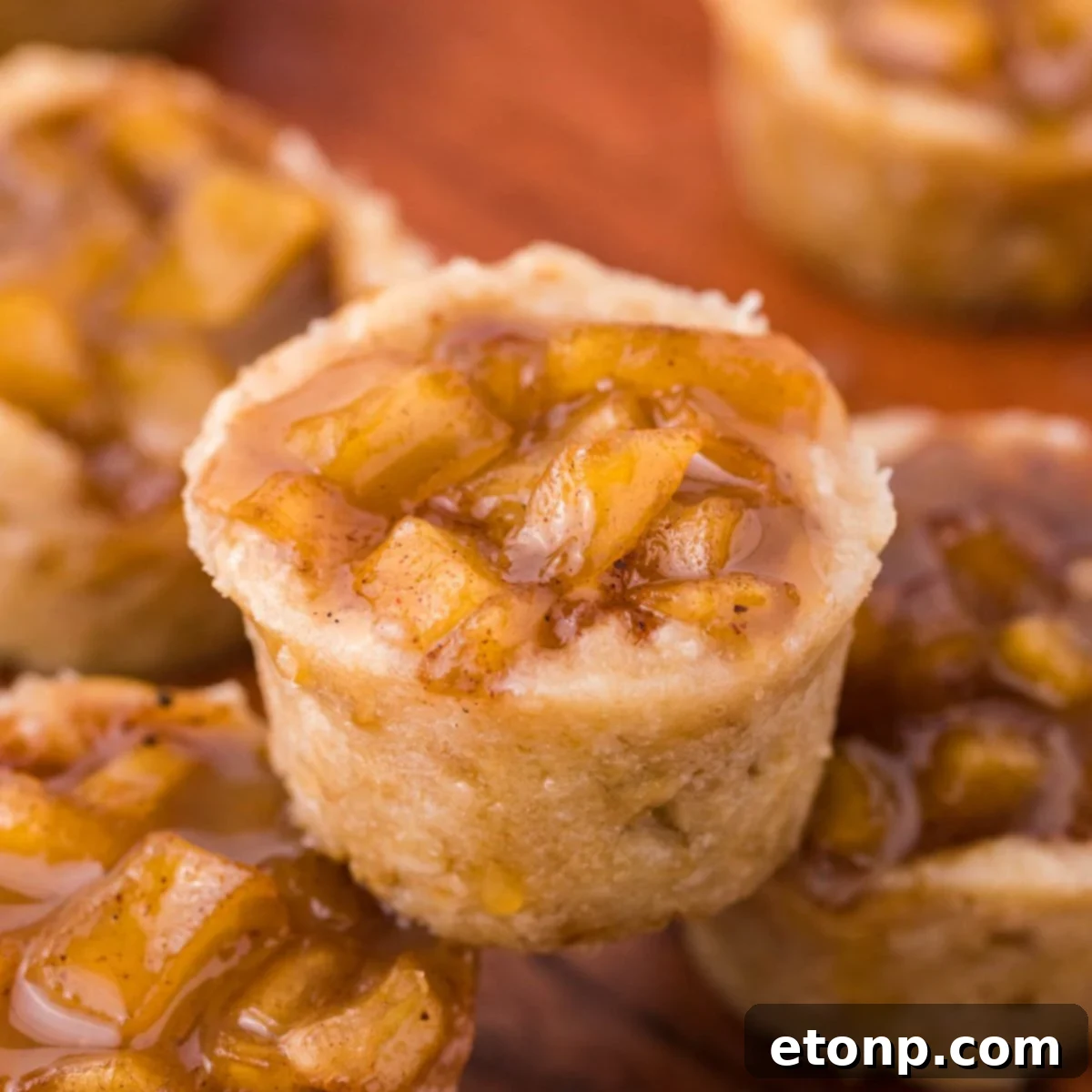 Mini Apple Crisp Bites placed around a wooden table with one stacked on top of another one 