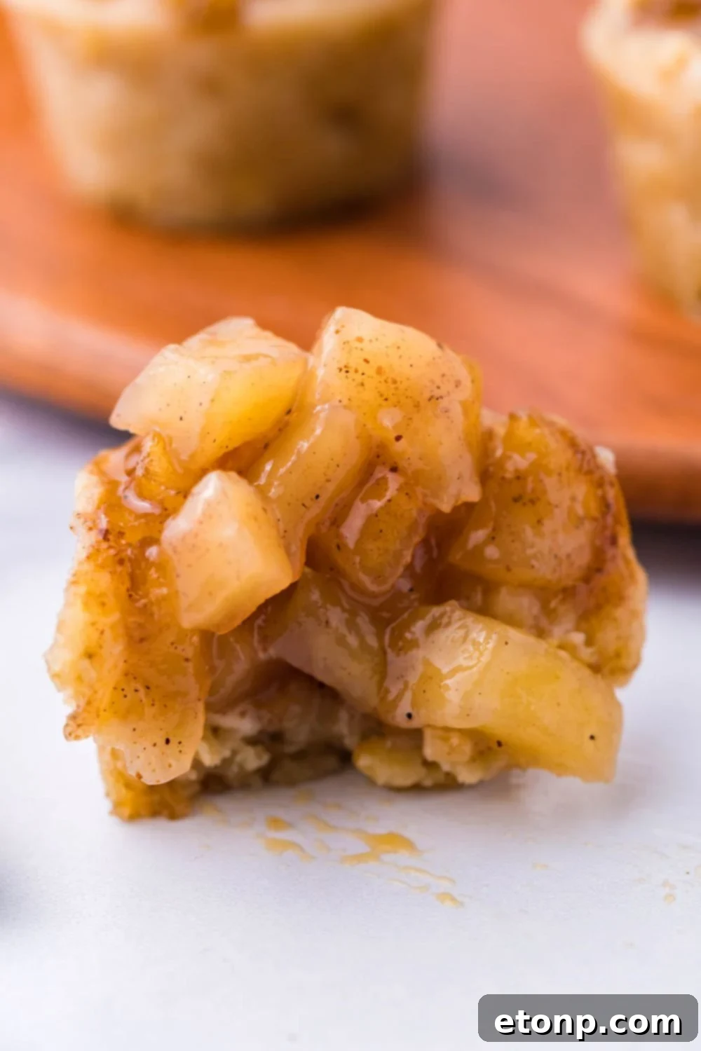bite taken out of a mini apple crisp bite cup, with a bunch of the apple filling on top 