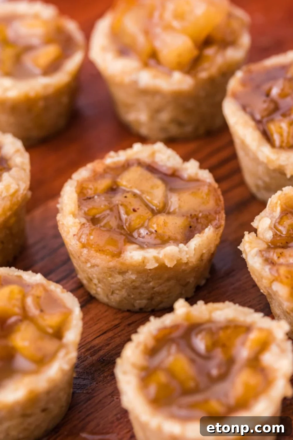Mini Apple Crisp Bites scattered on a wooden platter on table showing the sweet apple filling and oat base 