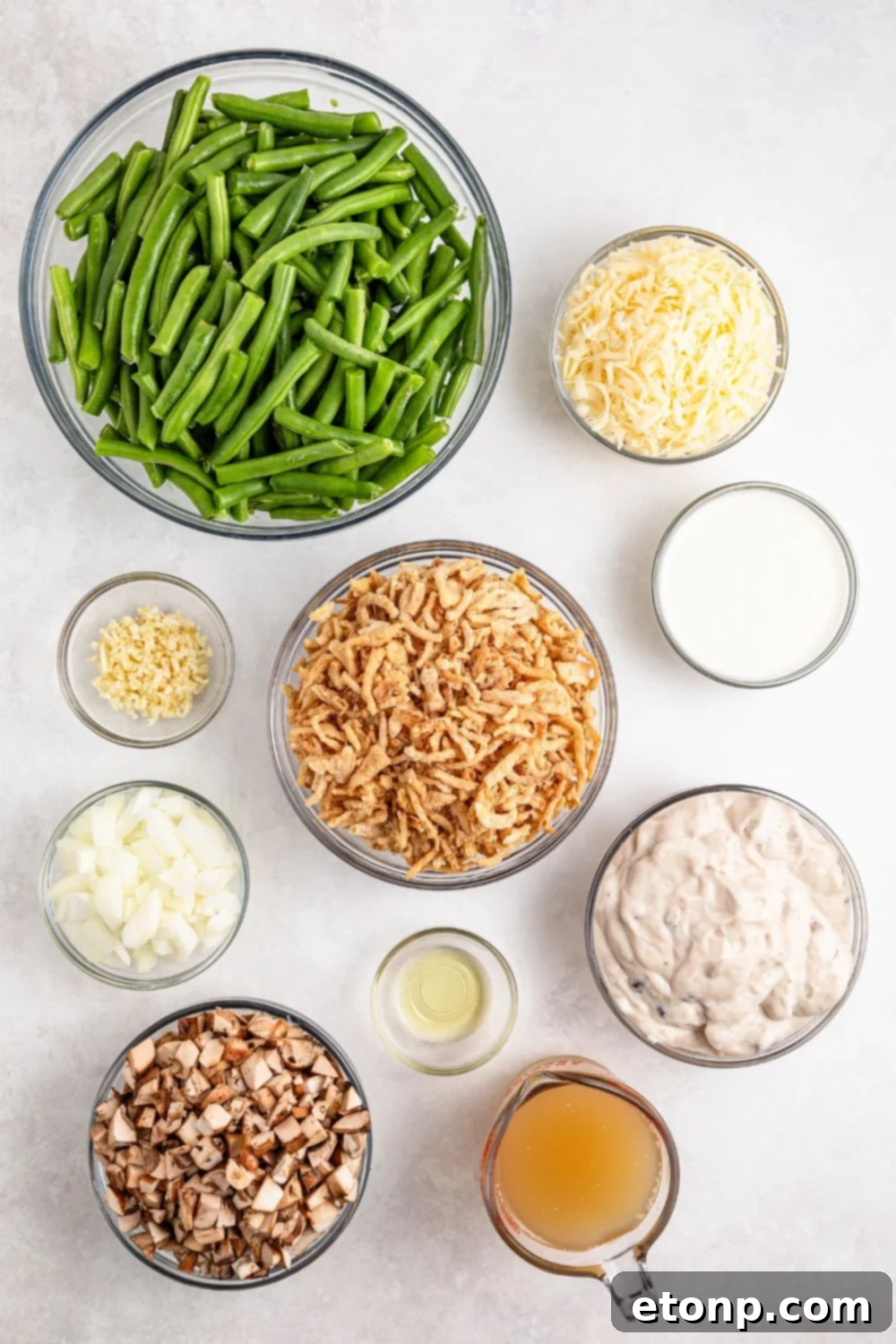 Green Bean Casserole ingredients in single serve bowls on table - green beans, garlic, onion, crispy fried onions, and more