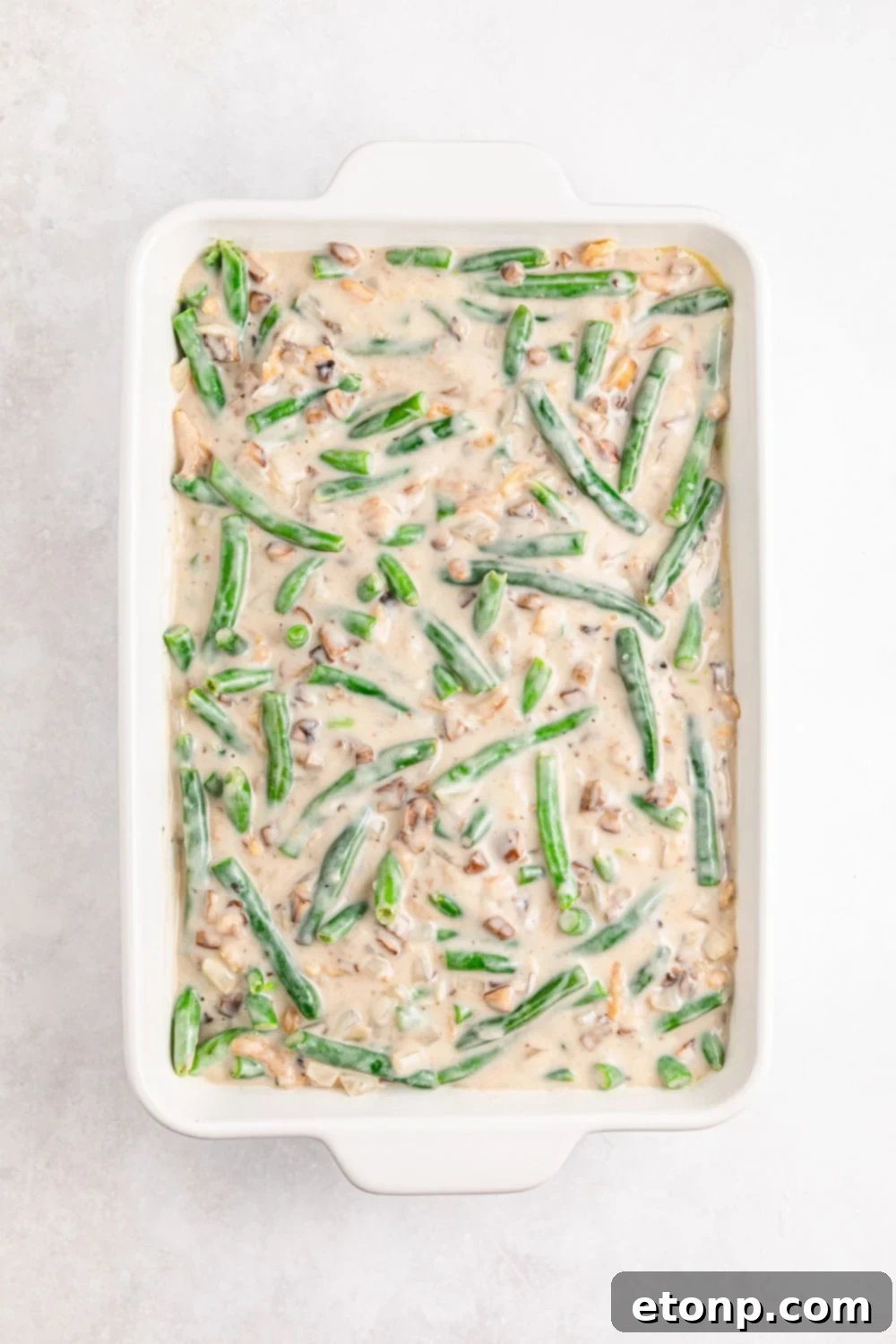 the mixture for Green Bean Casserole in a casserole dish with the green beans and the sauce 