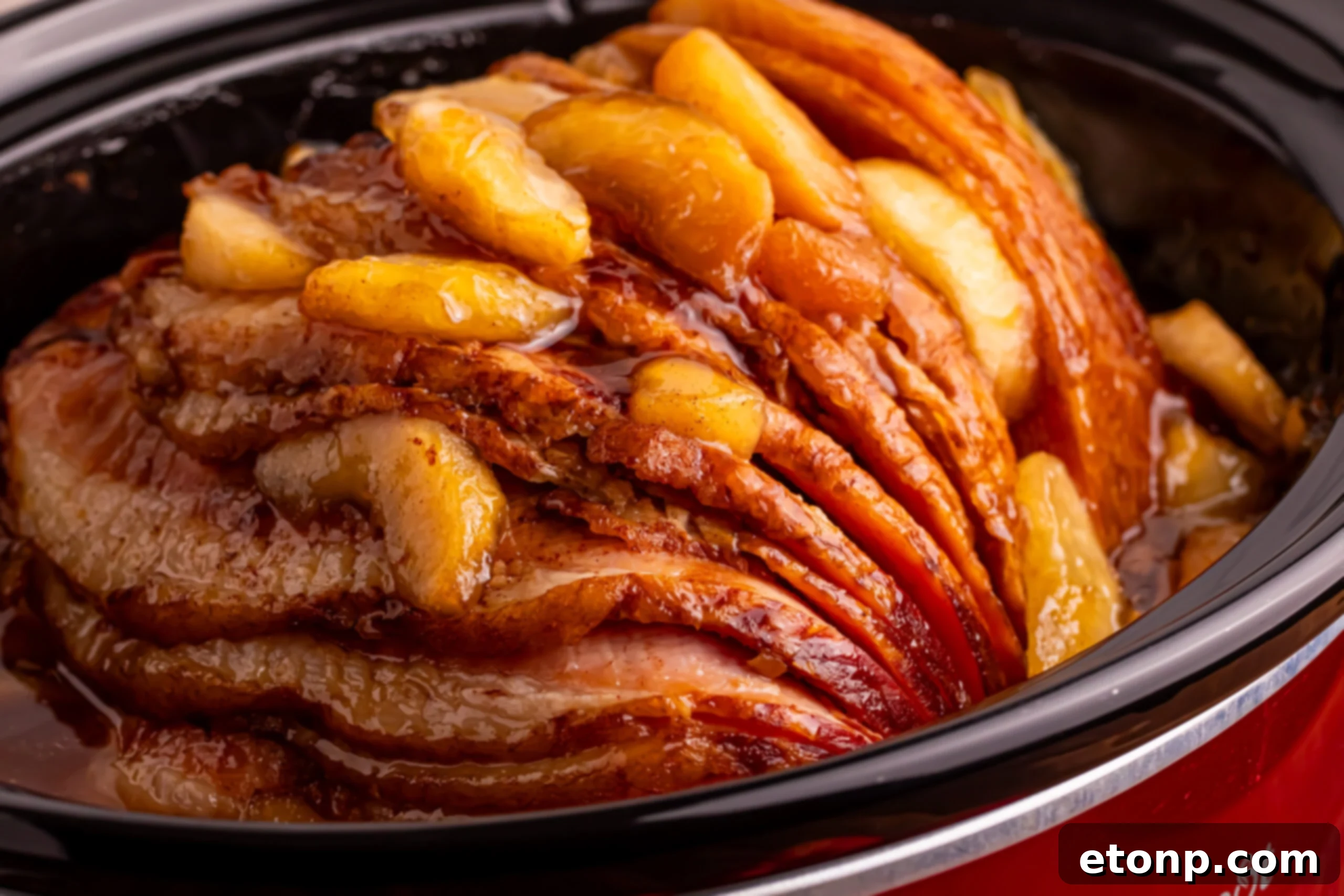 Side view of the Slow Cooker Apple Glazed Ham in a red slow cooker 
