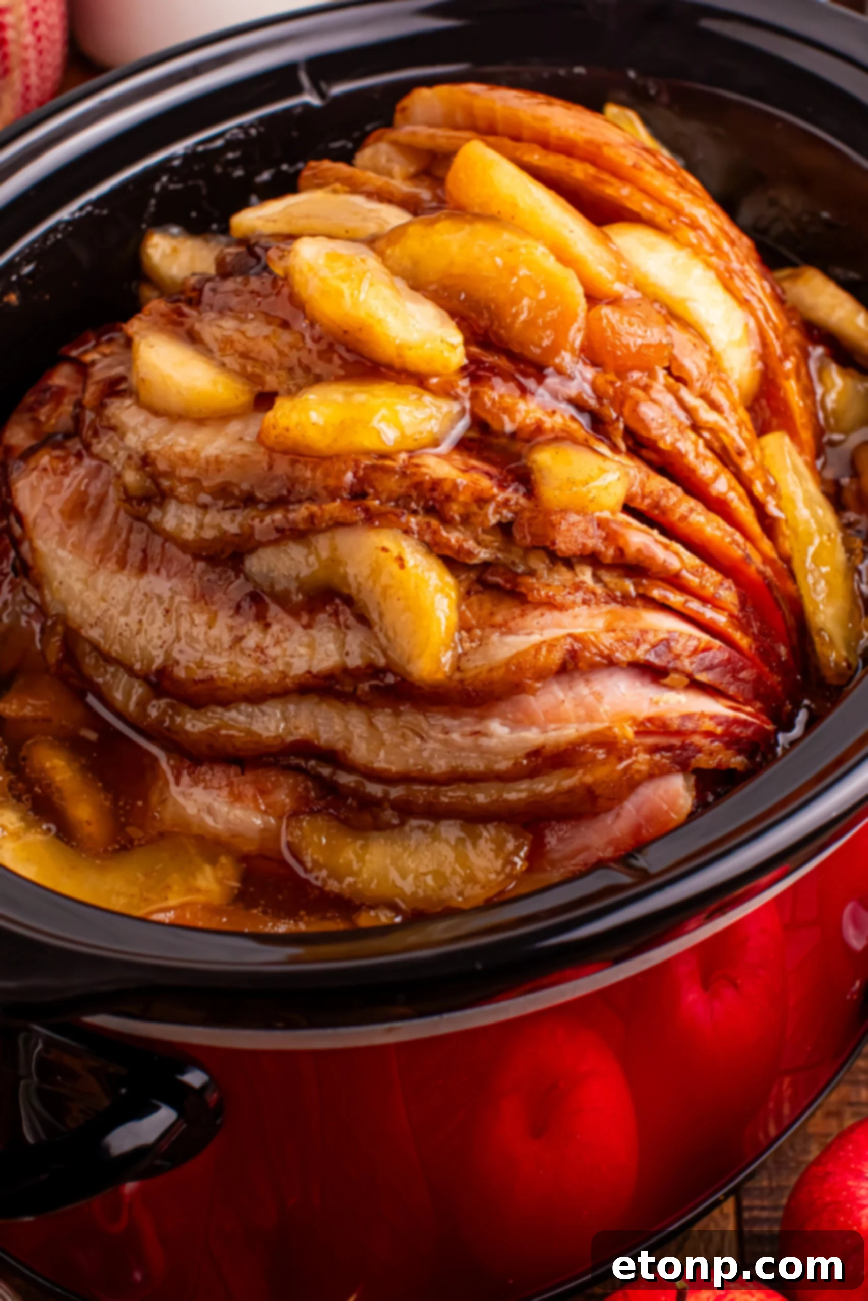 Slow Cooker Apple Glazed Ham in a black crock pot on a dark wood table 