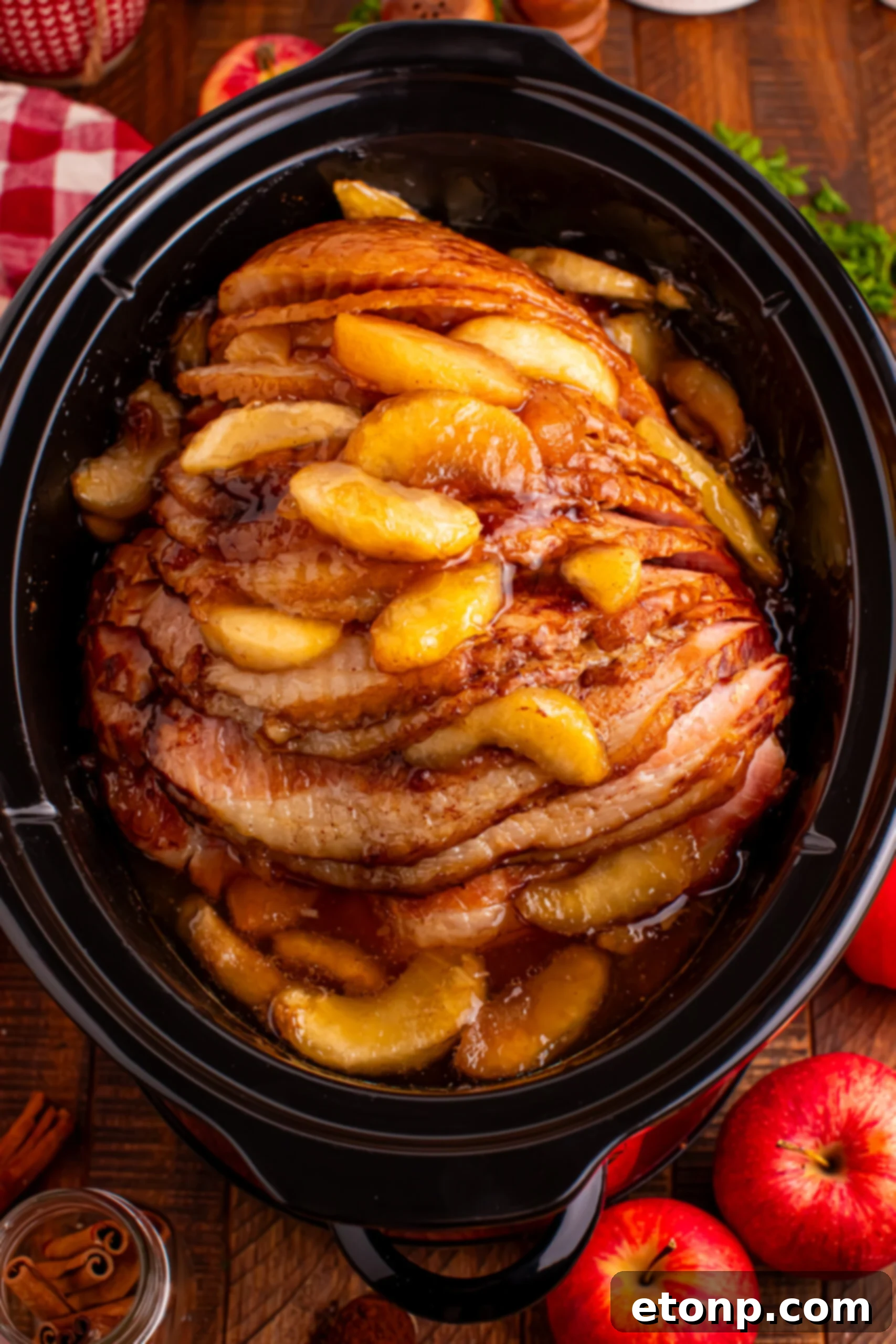 overhead shot of the cooked Slow Cooker Apple Glazed Ham in a black crock pot on a dark wood table 