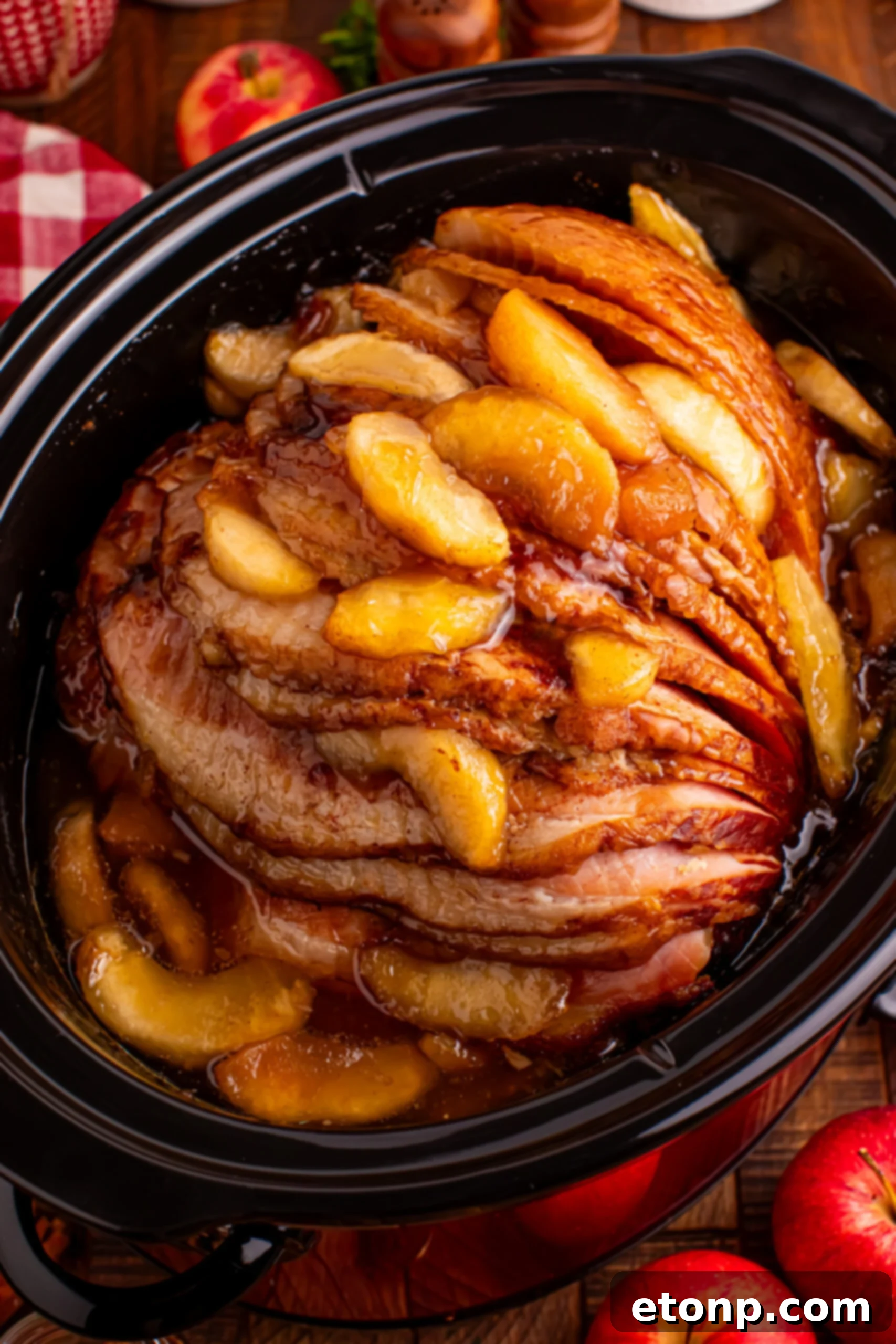 Slow Cooker Apple Glazed Ham in a black crock pot on a dark wood table 