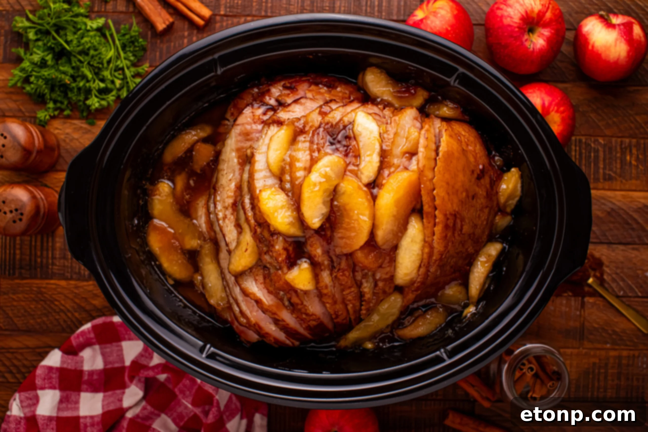Slow Cooker Apple Glazed Ham in a black crock pot on a dark wood table 