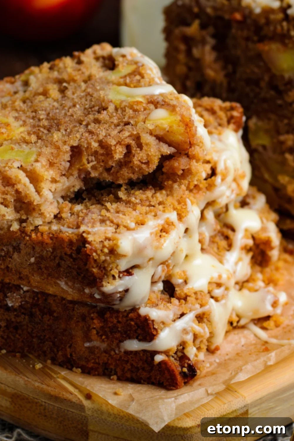 a few slices of Apple Cinnamon Loaf Cake stacked on top of one another with a few bites taken out of the top loaf sitting on a wooden cutting board