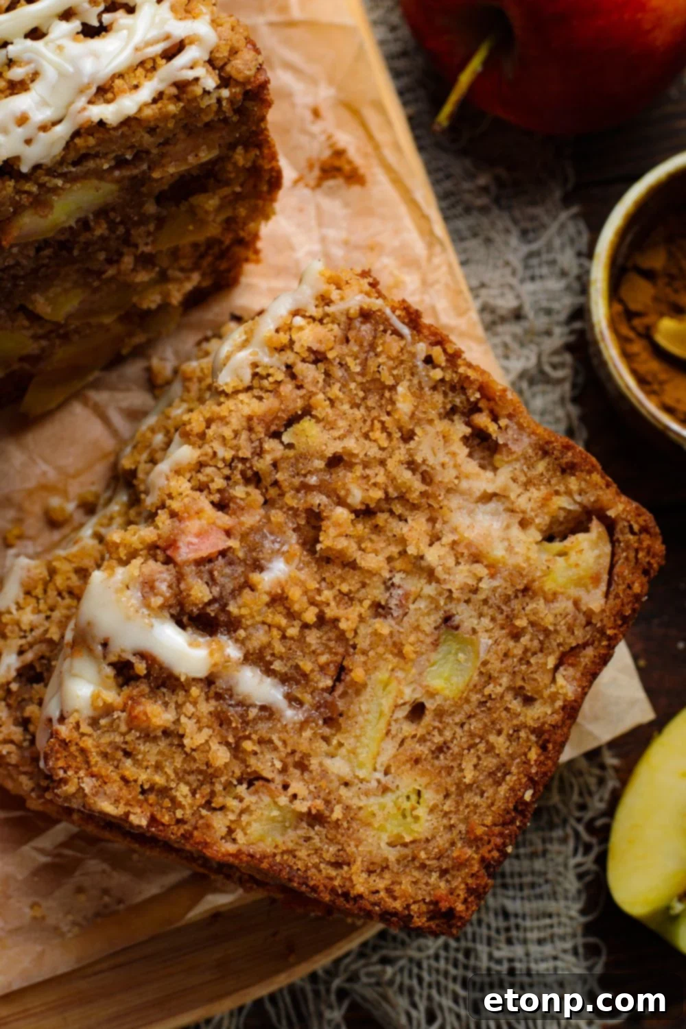 spatula on table with a slice of Apple Cinnamon Loaf Cake on it and a small bowl of cinnamon off to the side