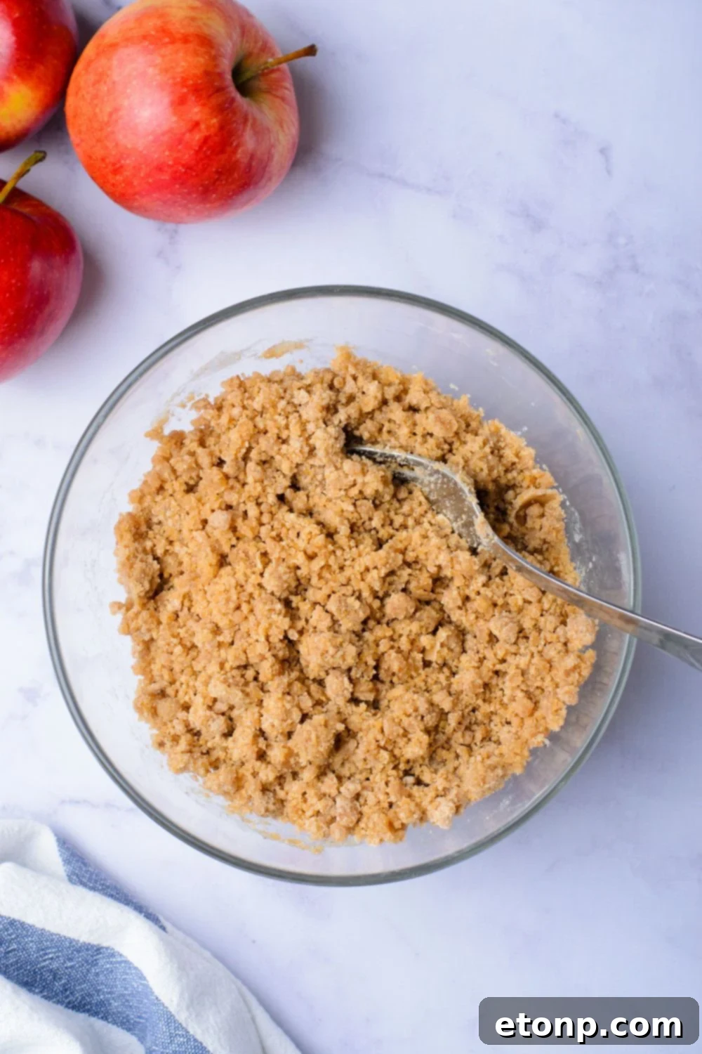 cinnamon sugar mixture in a glass bowl on table with two apples to the side