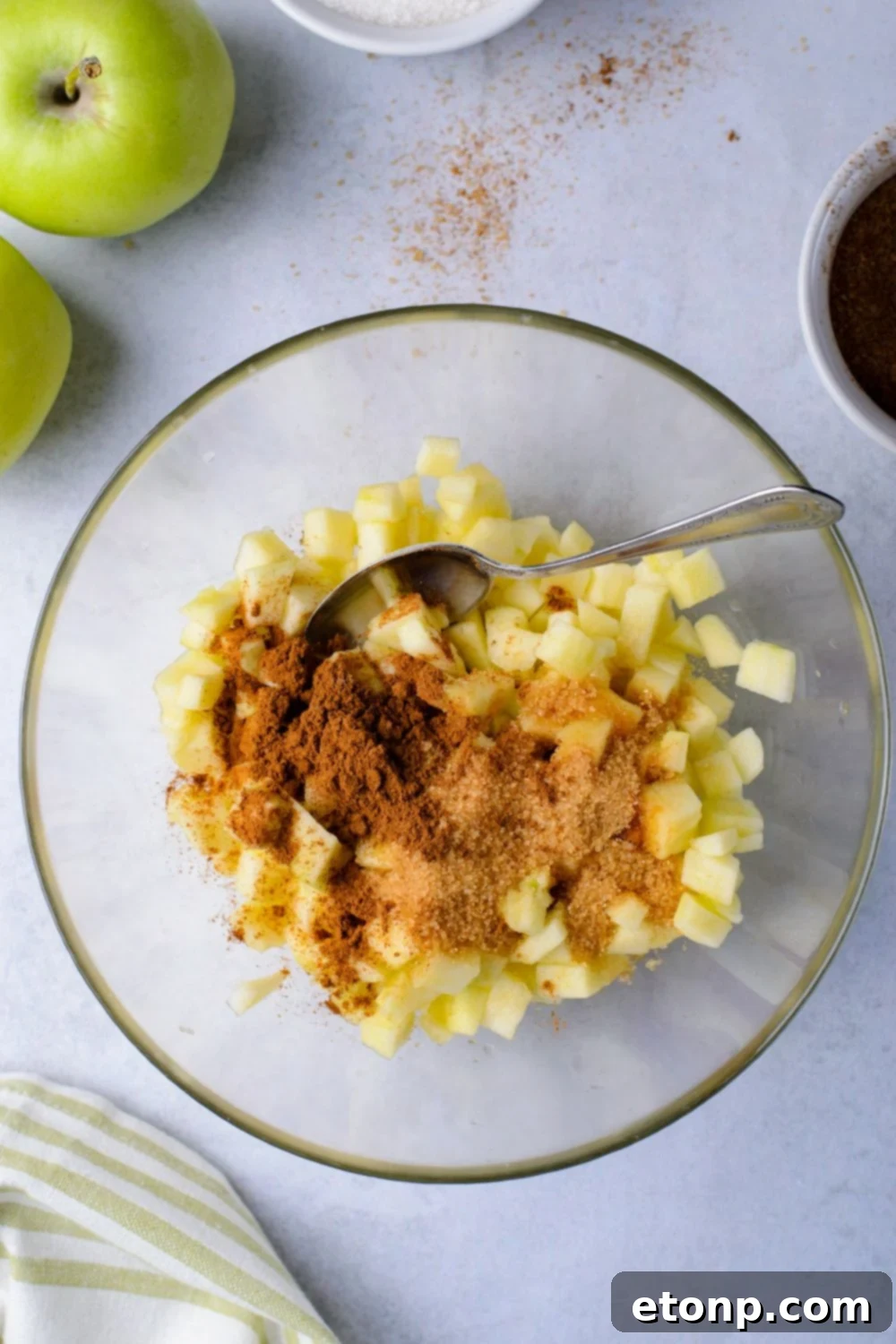 fresh diced apples in a bowl with some cinnamon on top and a spoon in bowl to mix