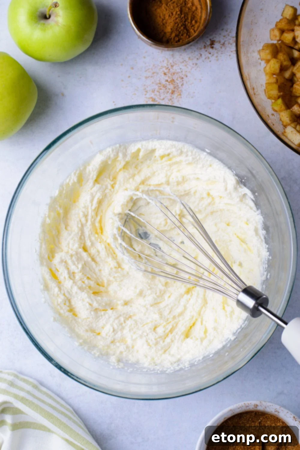 glass bowl with a whisk in it with wet ingredients for the Amish Apple Fritter Bread batter