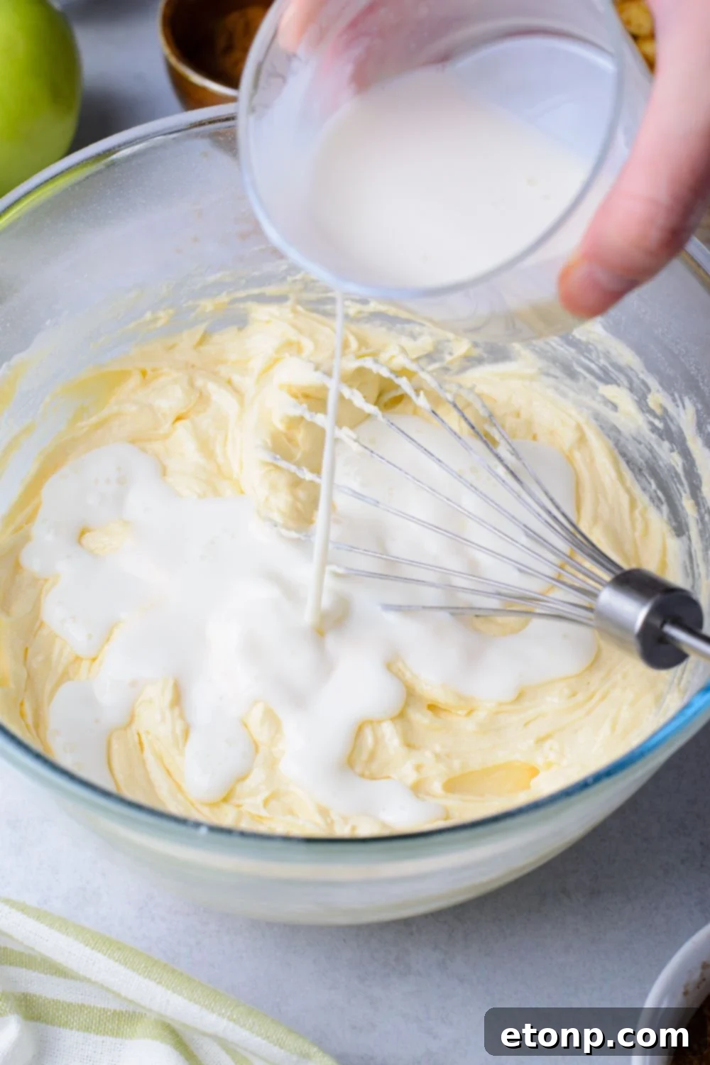 milk mixture pouring into an apple bread batter on table