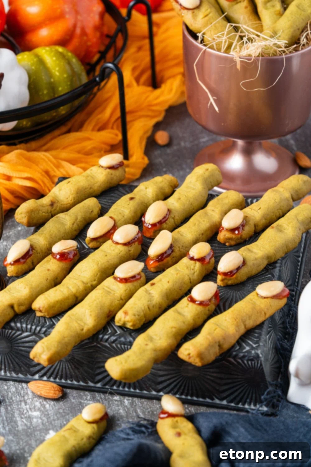witches finger on a cooling rack on table with fall themed items behind it on table 