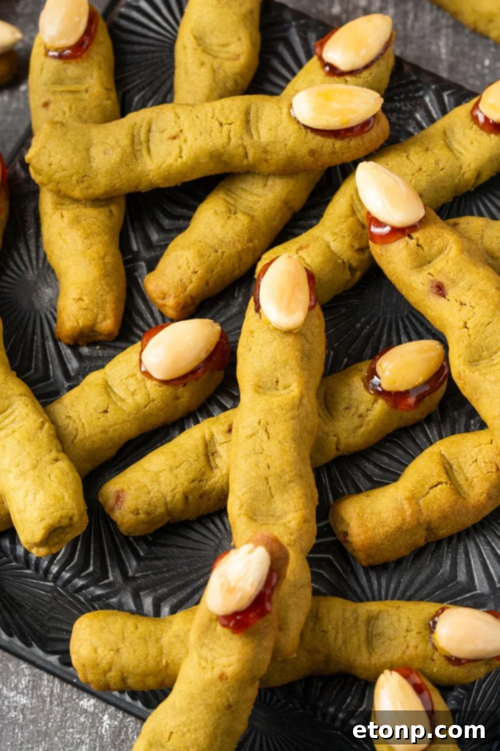 Witch Finger Cookies scattered all around the table and placed on a black tray 