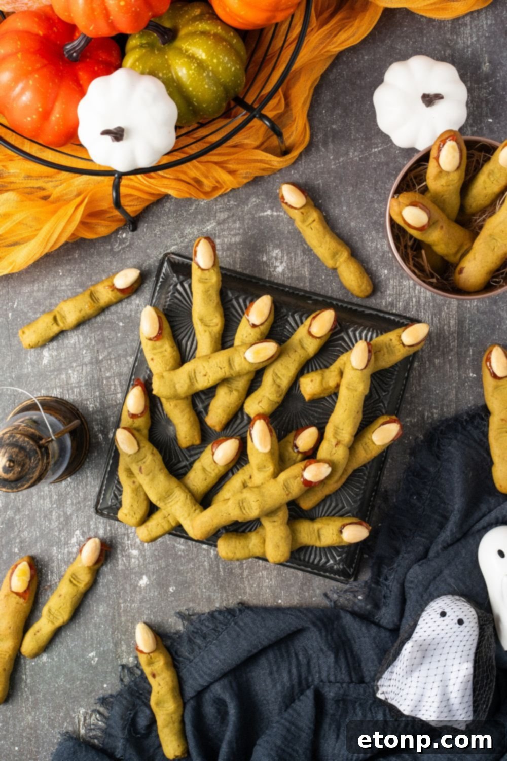Witch Finger Cookies in a square plate on table with more scattered around the table with Halloween decor all around table 