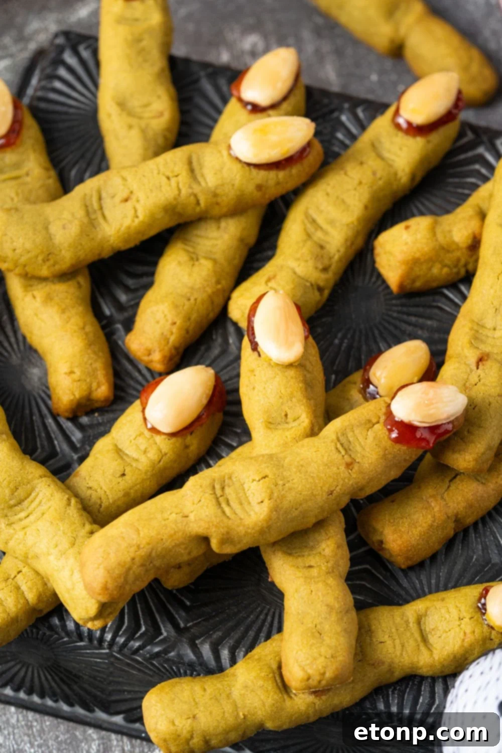 Witch Finger Cookies placed all around on a black square plate with cookies stacked on top of one another 