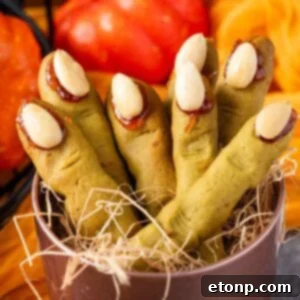 Witch Finger Cookies in a basket with straw in it with pumpkins and leaves on the table behind it