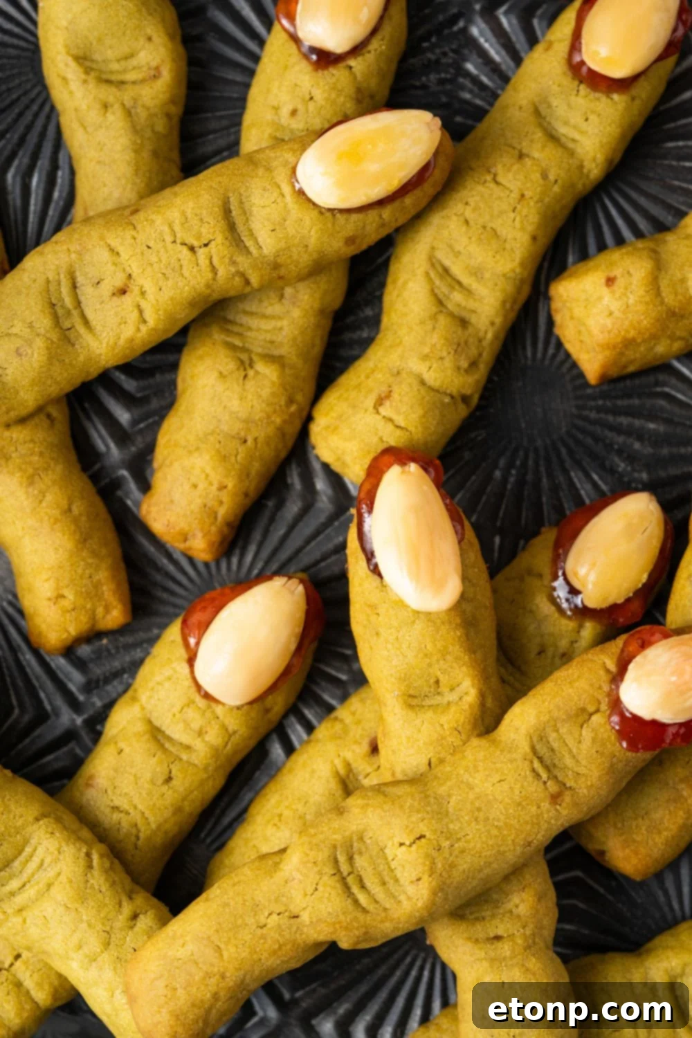 Witch Finger Cookies on a black tray. The cookies are scattered around the tray