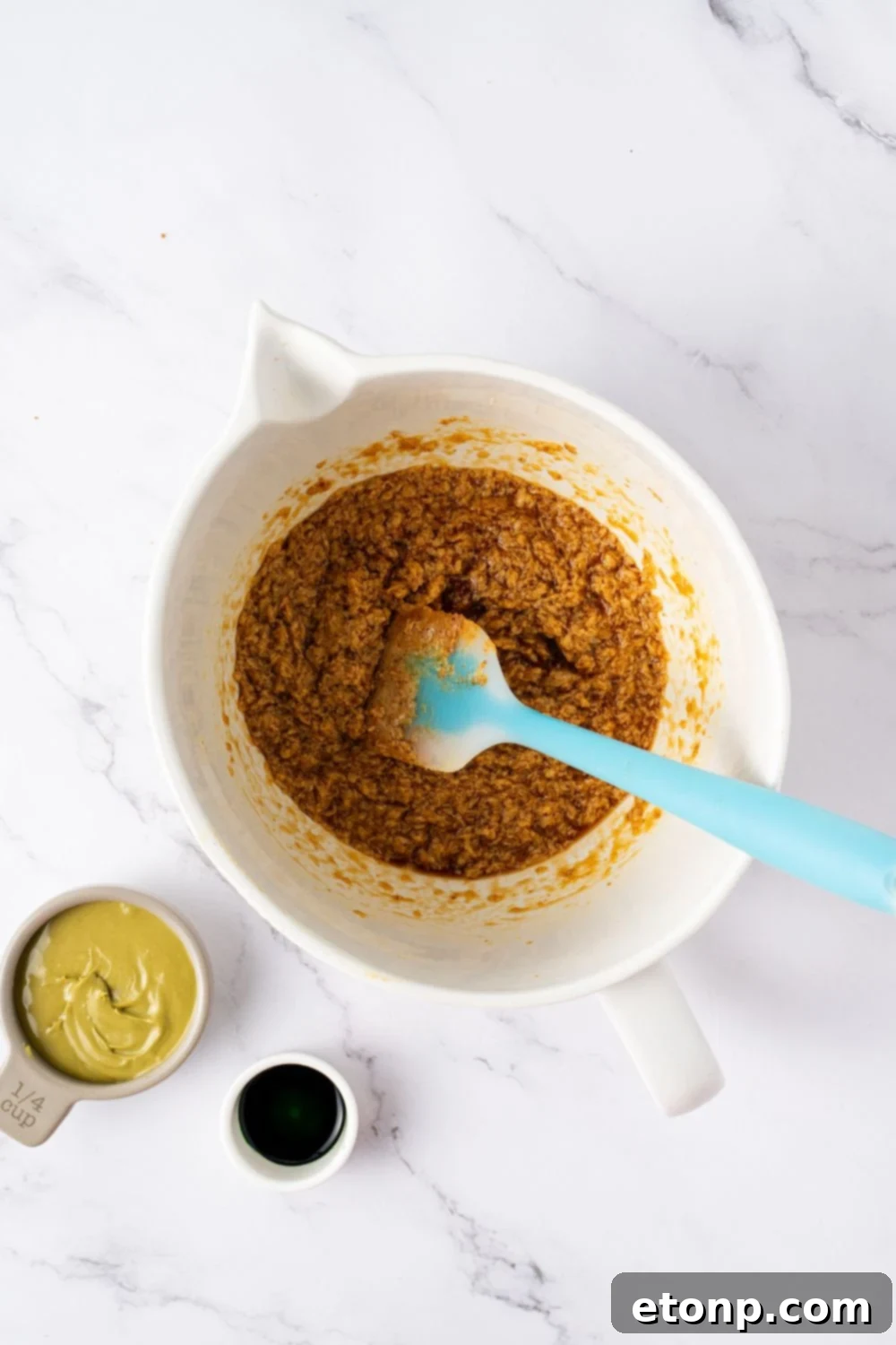 cookie dough batter in a bowl being mixed together with a blue and white spatula 