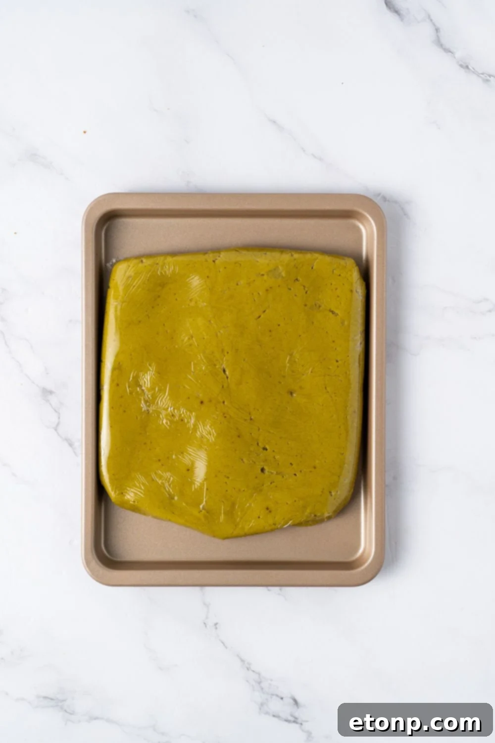 pistachio cookie dough shaped in a square on a baking sheet on table 