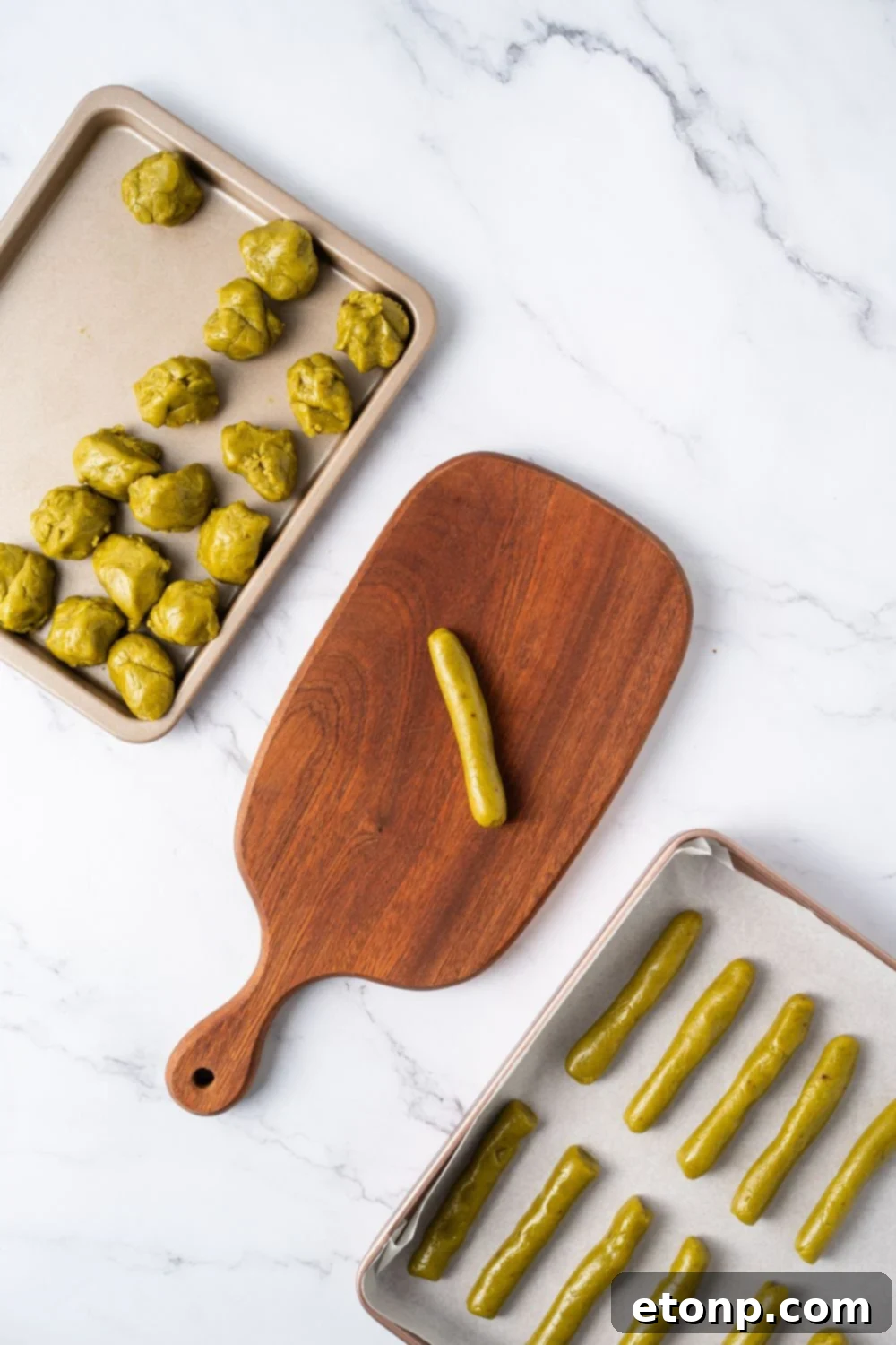 Witch Finger Cookie dough on a tray with a wooden tray with a shape of fingers and another tray with balls of cookie dough 