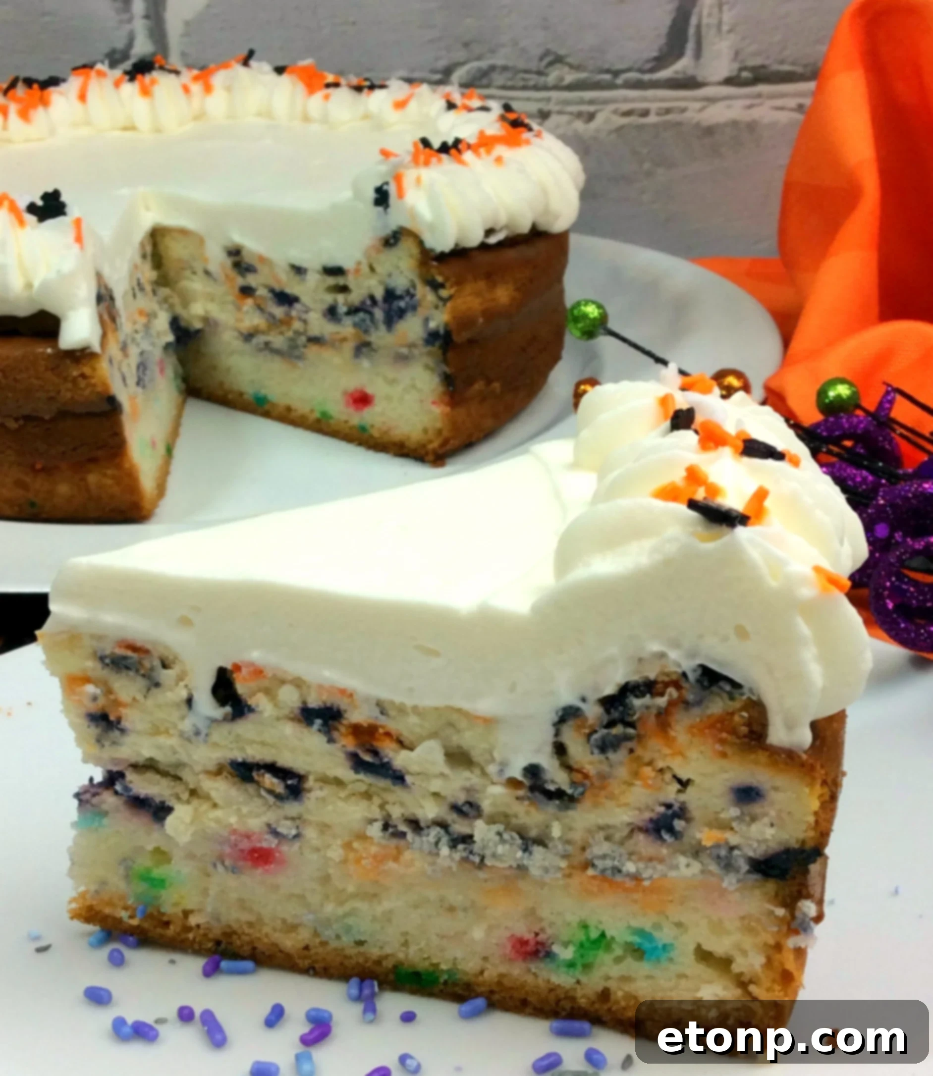 Halloween Cheesecake with a generous layer of whipped cream and colorful sprinkles