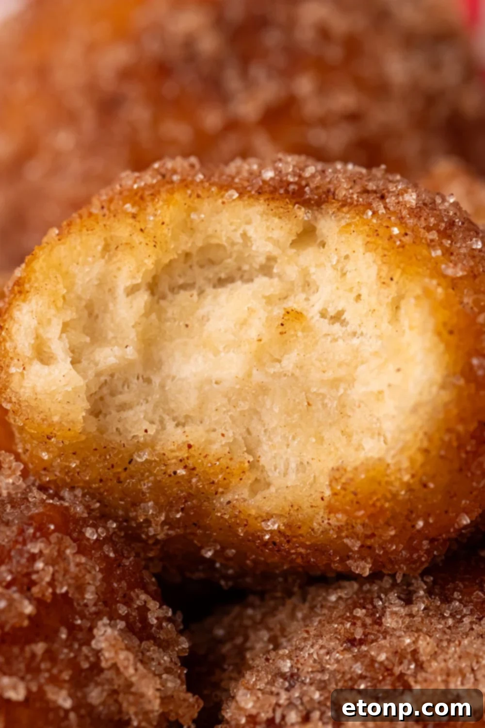 a bite taken out of an Apple Pie Donut Hole that is showing a close up view to show how fluffy it is 