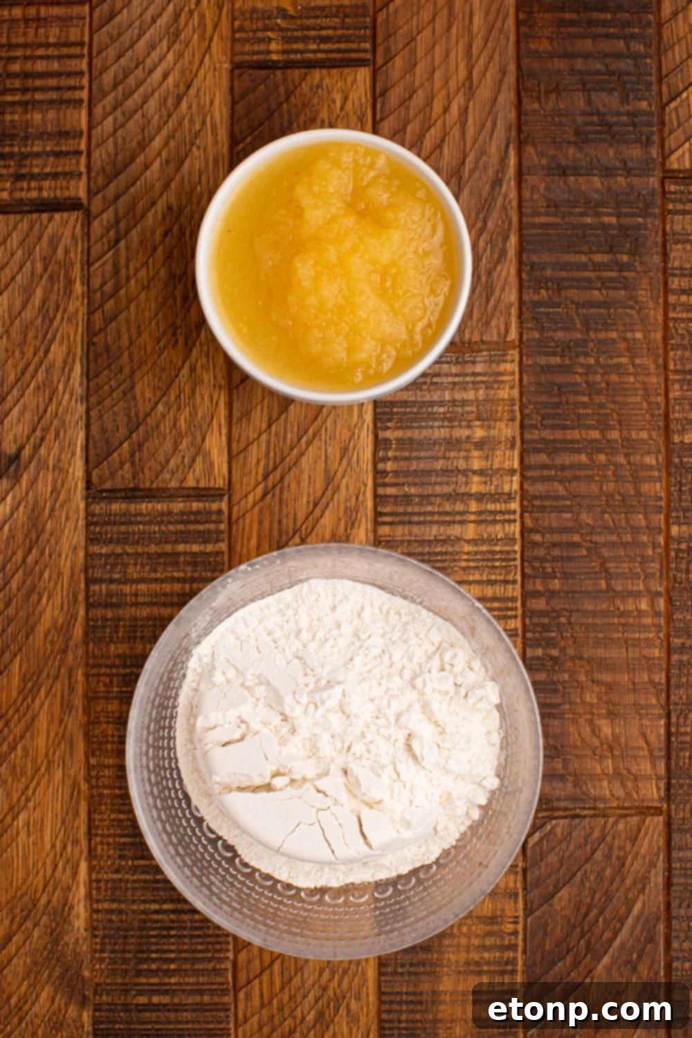 glass bowl of self rising flour and applesauce in a bowl on wooden table 