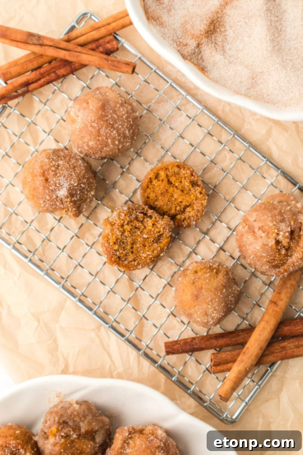 Pumpkin Spice Donut Holes on a cooling rack with cinnamon sticks around the edges of the rack