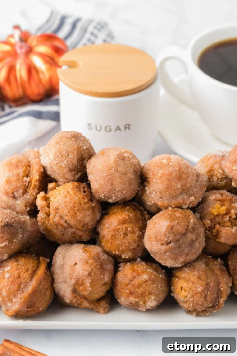 white rectangle chair on table stacked with pumpkin donut holes, and a cup of coffee and fall decor behind it on the table 