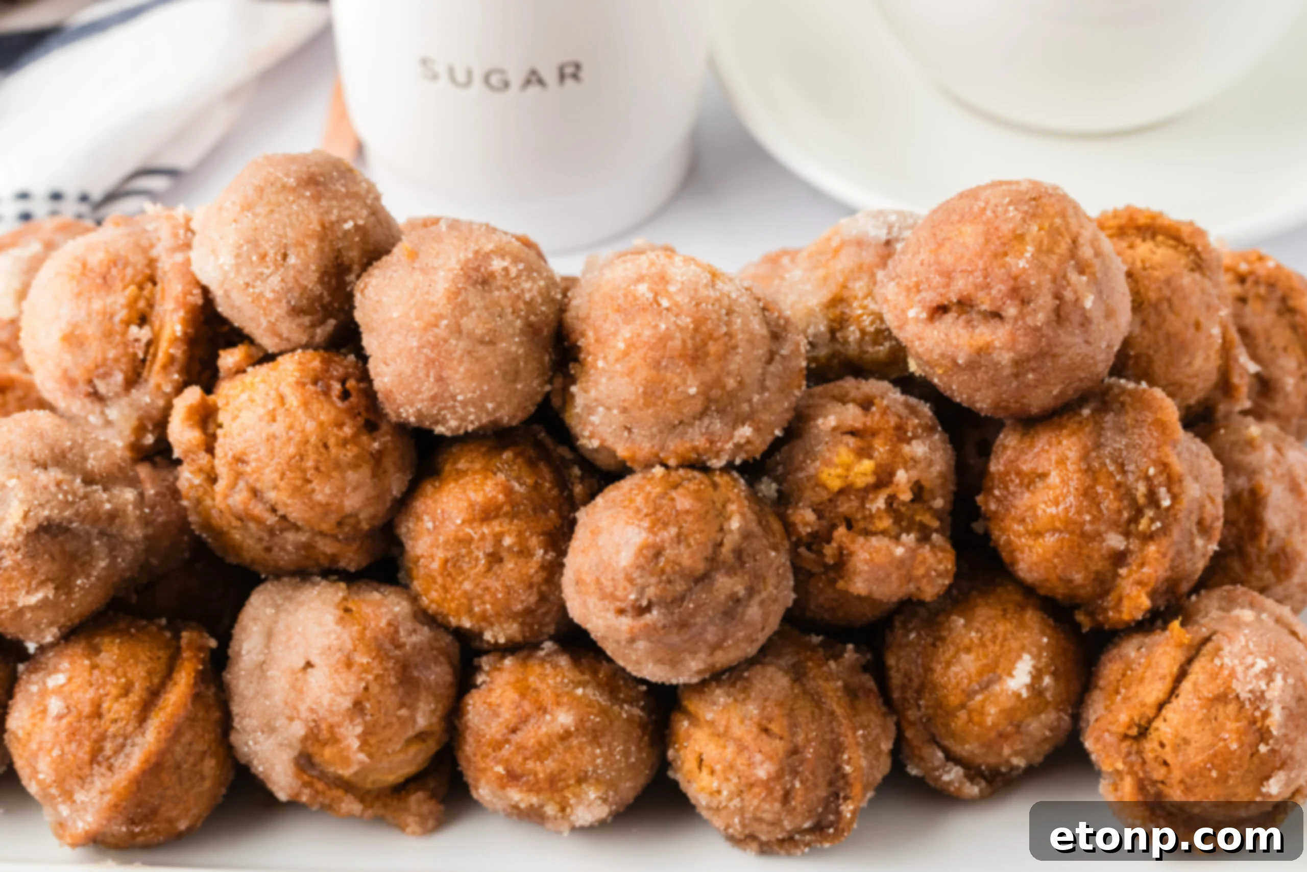 a huge bunch of the Pumpkin Spice Donut Holes on a white plate with a containe