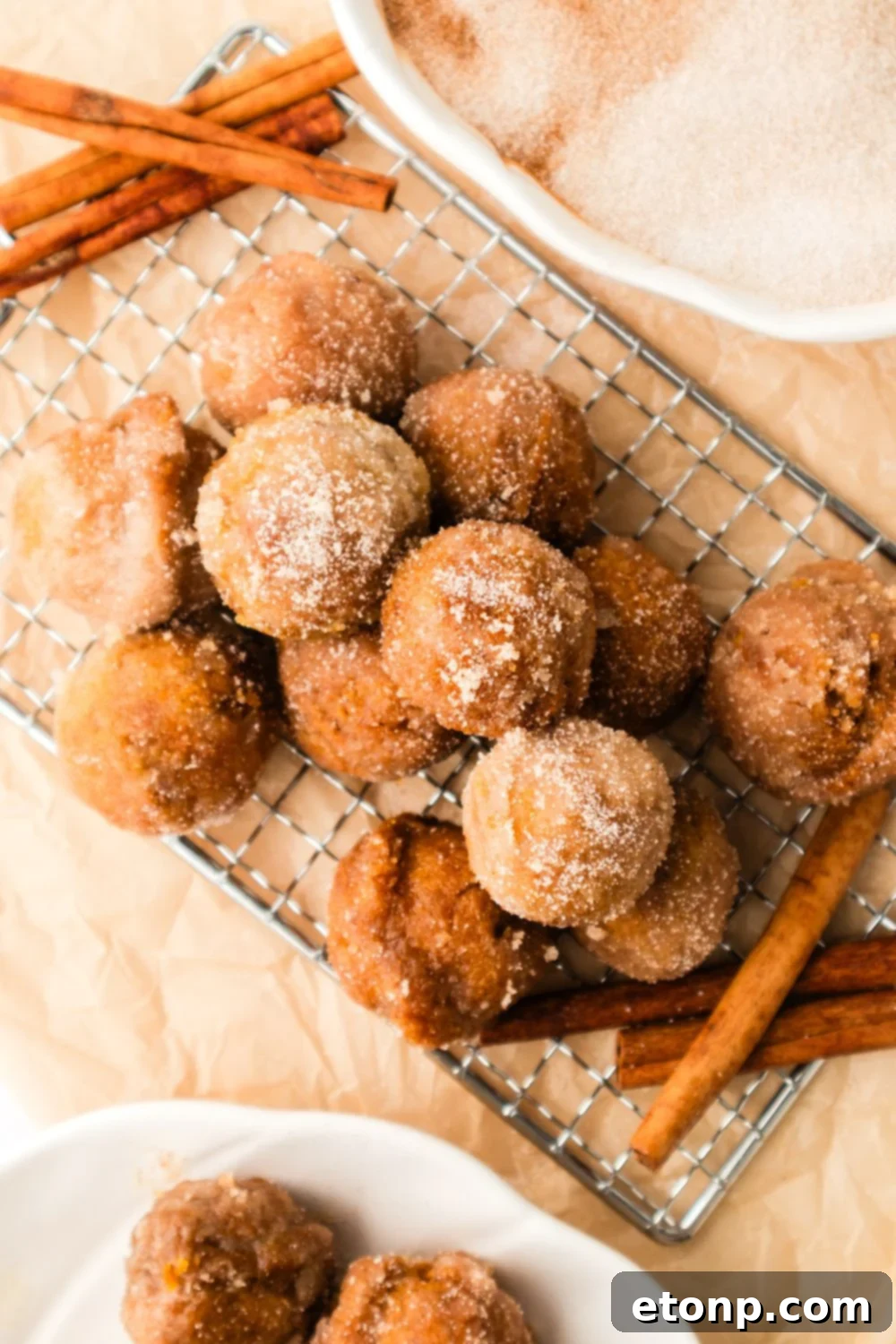 Pumpkin Spice Donut Holes on a metal tray with a few cinnamon sticks to the side 