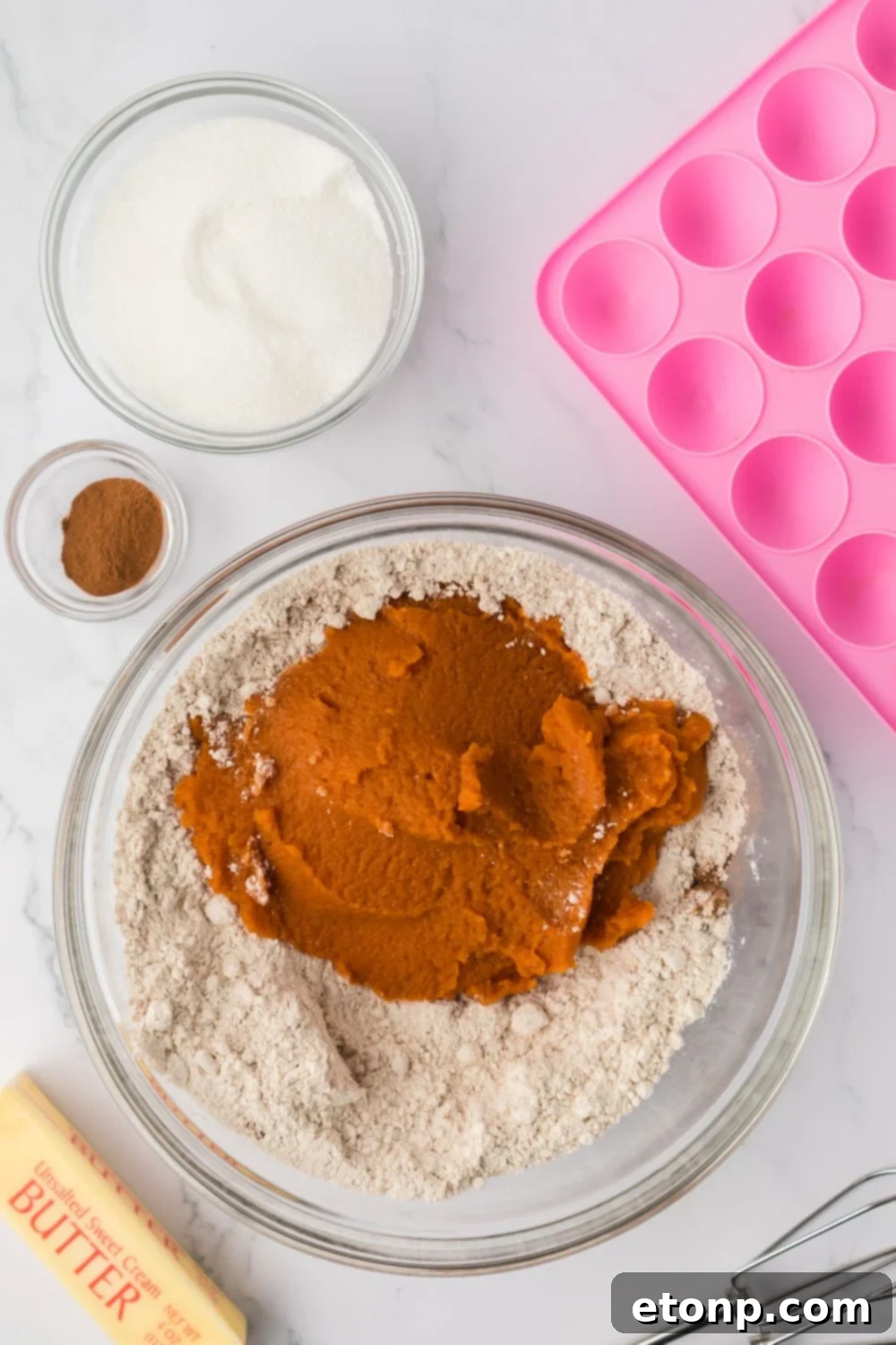 dry ingredients and pumpkin puree in a glass bowl on a marble counter 