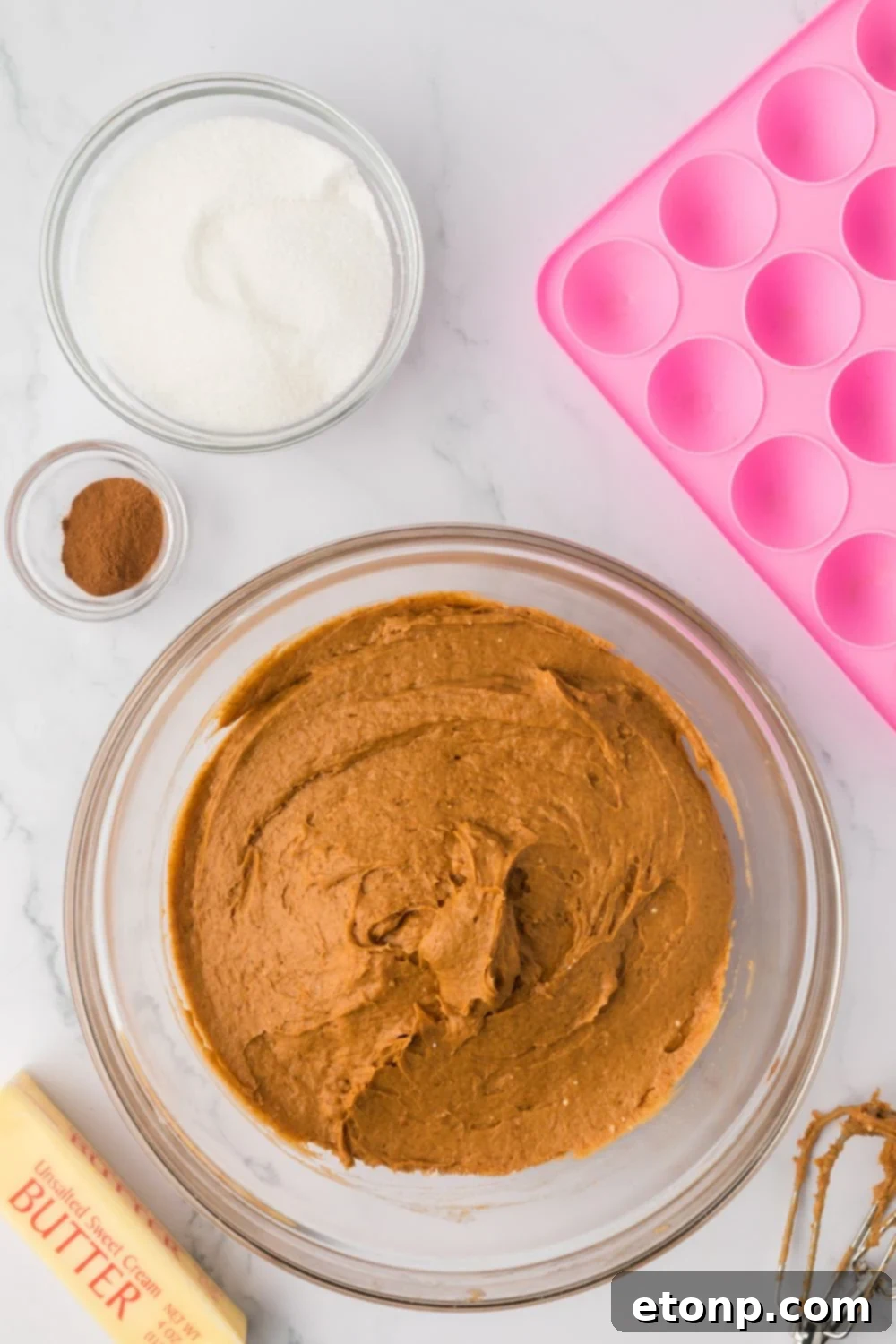 a glass bowl with Pumpkin Spice Donut Hole batter in it, with the donut pan to the side 