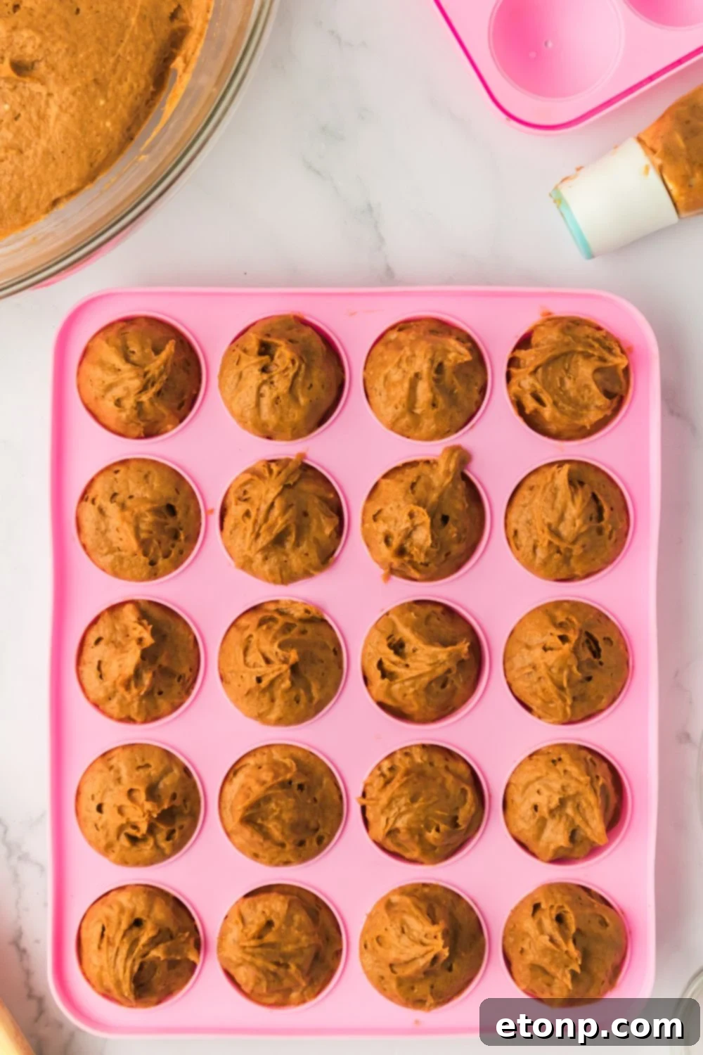 raw batter for Pumpkin Spice Donut Holes in a pink donut pan sitting on a marble counter 