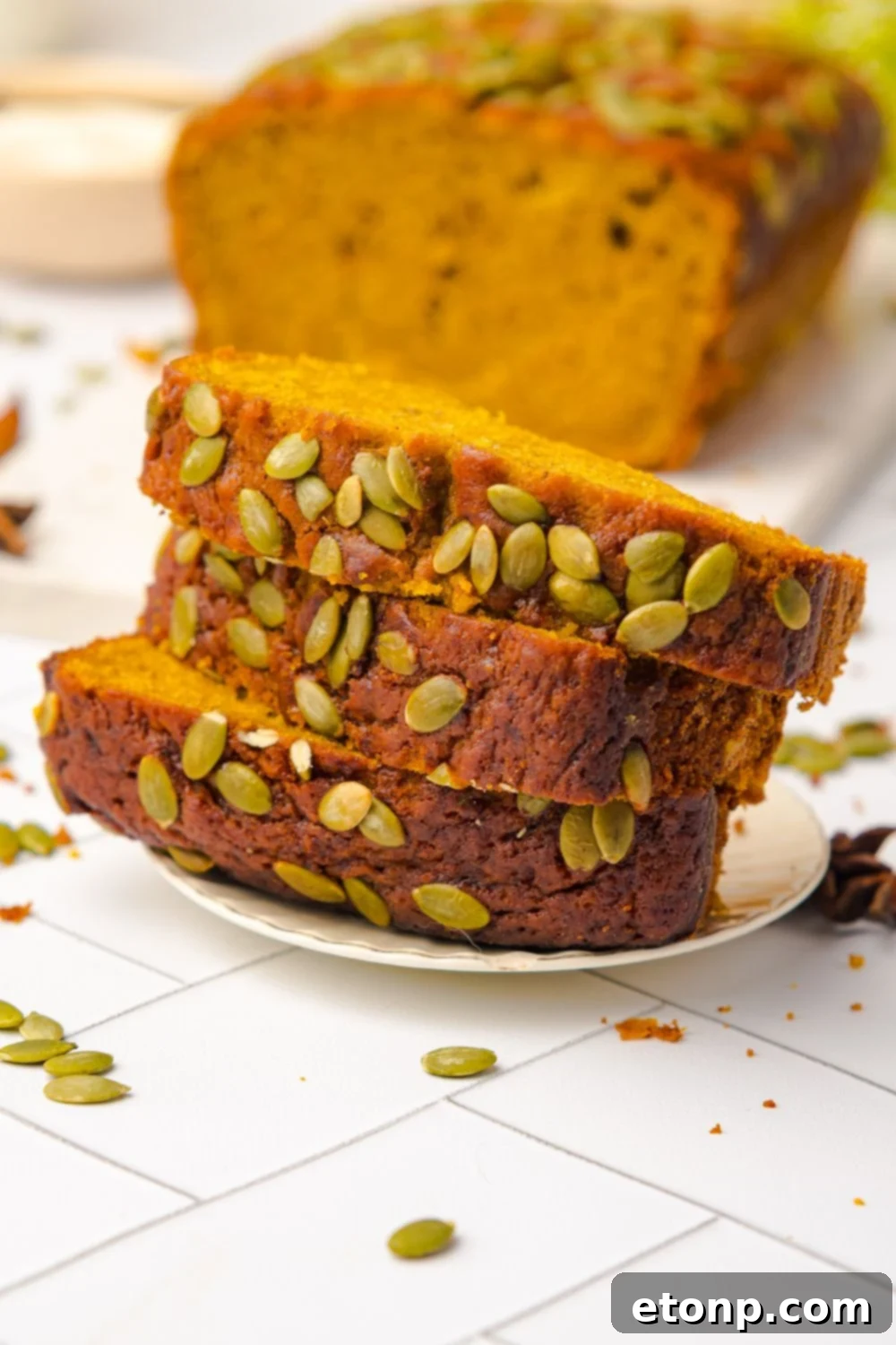 small white plate with a stack of Starbucks Pumpkin Bread on it, and the rest of the loaf behind it on table 