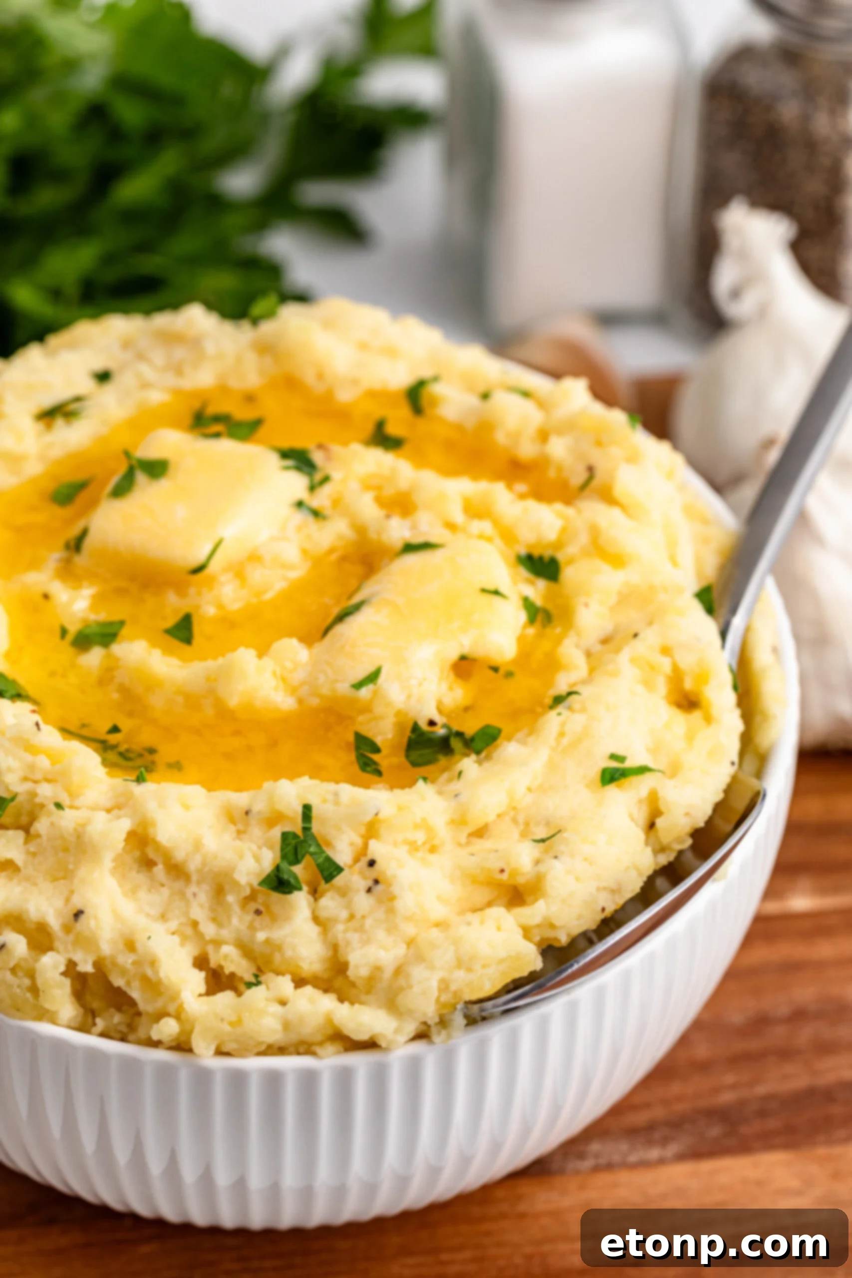 Garlic mashed potatoes in a white bowl on a dark wood table, ready to be served